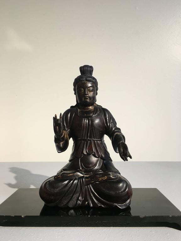 A finely carved Chinese zitan wood figure of an unidentified bodhisattva, possibly Guanyin, late Qing Dynasty, circa 1900, China.
The androgynous figure has a plump, almost matronly face, with downcast eyes and a gentle smile. The hair in long