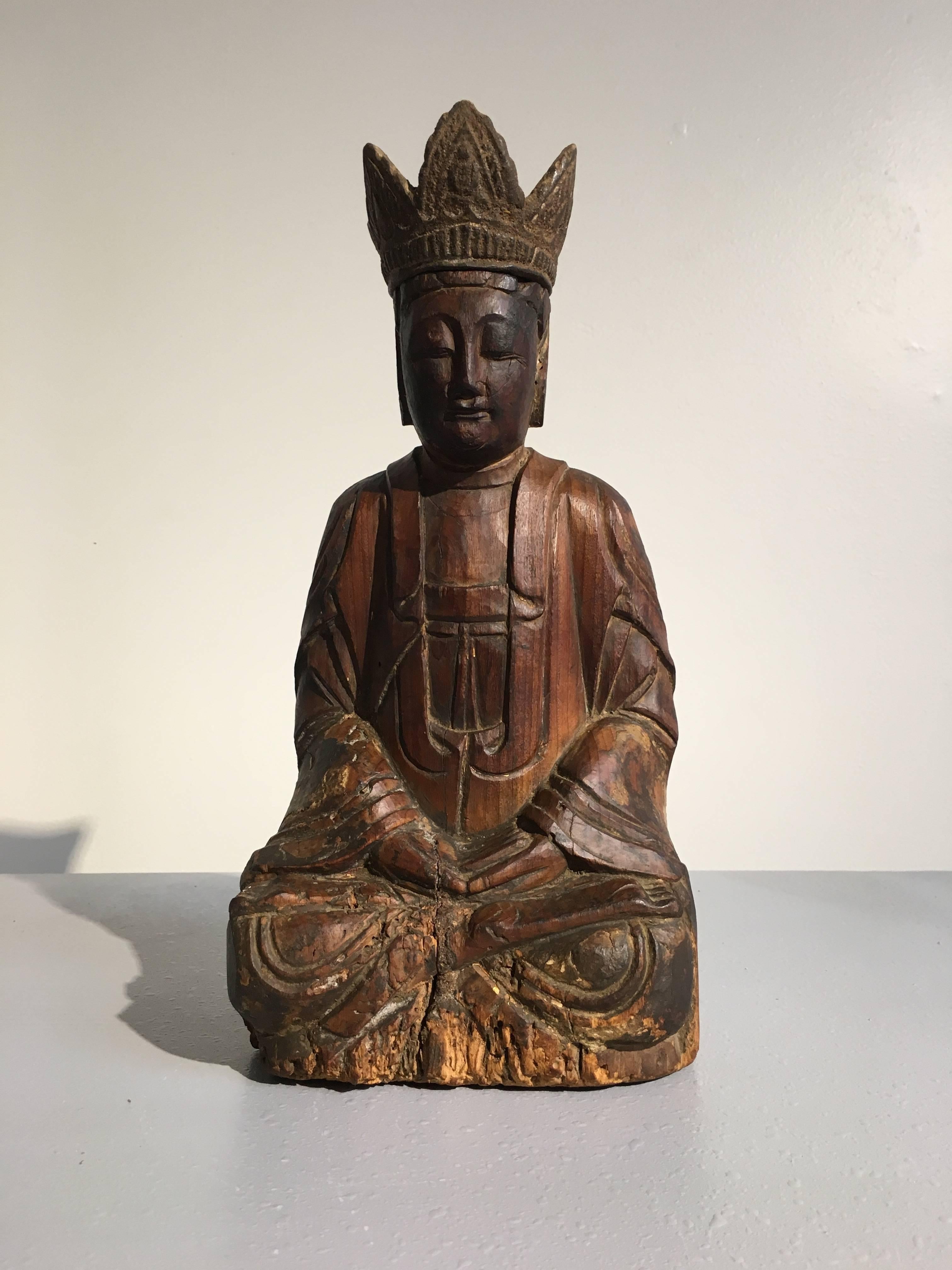 An attractive carved wood figure of the Bodhisattva Avalokiteshvara, known as Guanyin in China, late Ming Dynasty, early 17th century, China.

Guanyin, the Bodhisattva of Compassion, also known as Avalokiteshvara, sits calmly in dhyanasana, legs
