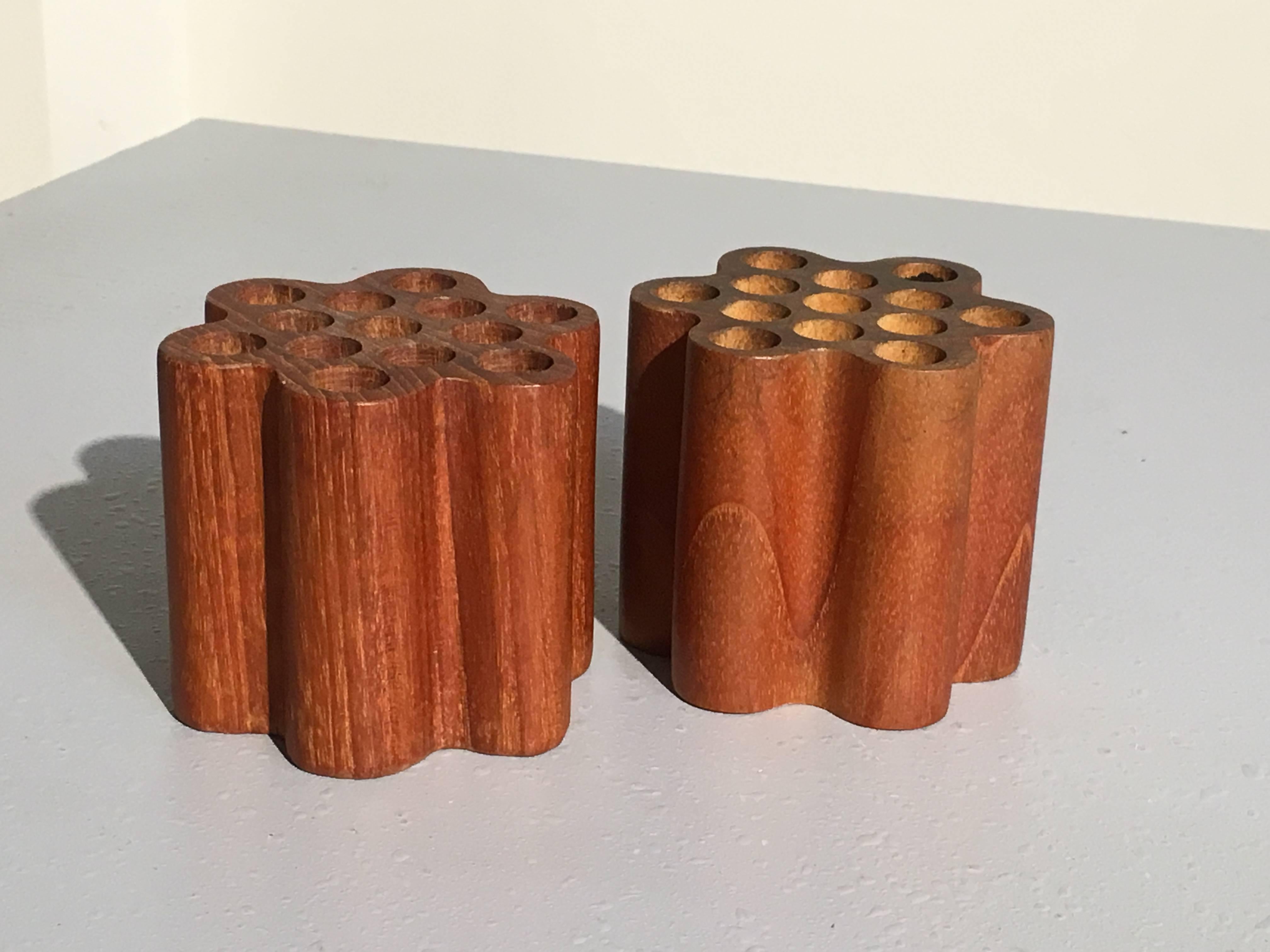 A pair of Swedish modernist pen or pencil holders originally made for and retailed by Bonniers, New York city. 
Carved of solid teak, the sleek and elegant design in the form of streamlined lotus pods or honeycombs. Each pod/comb capable of holding
