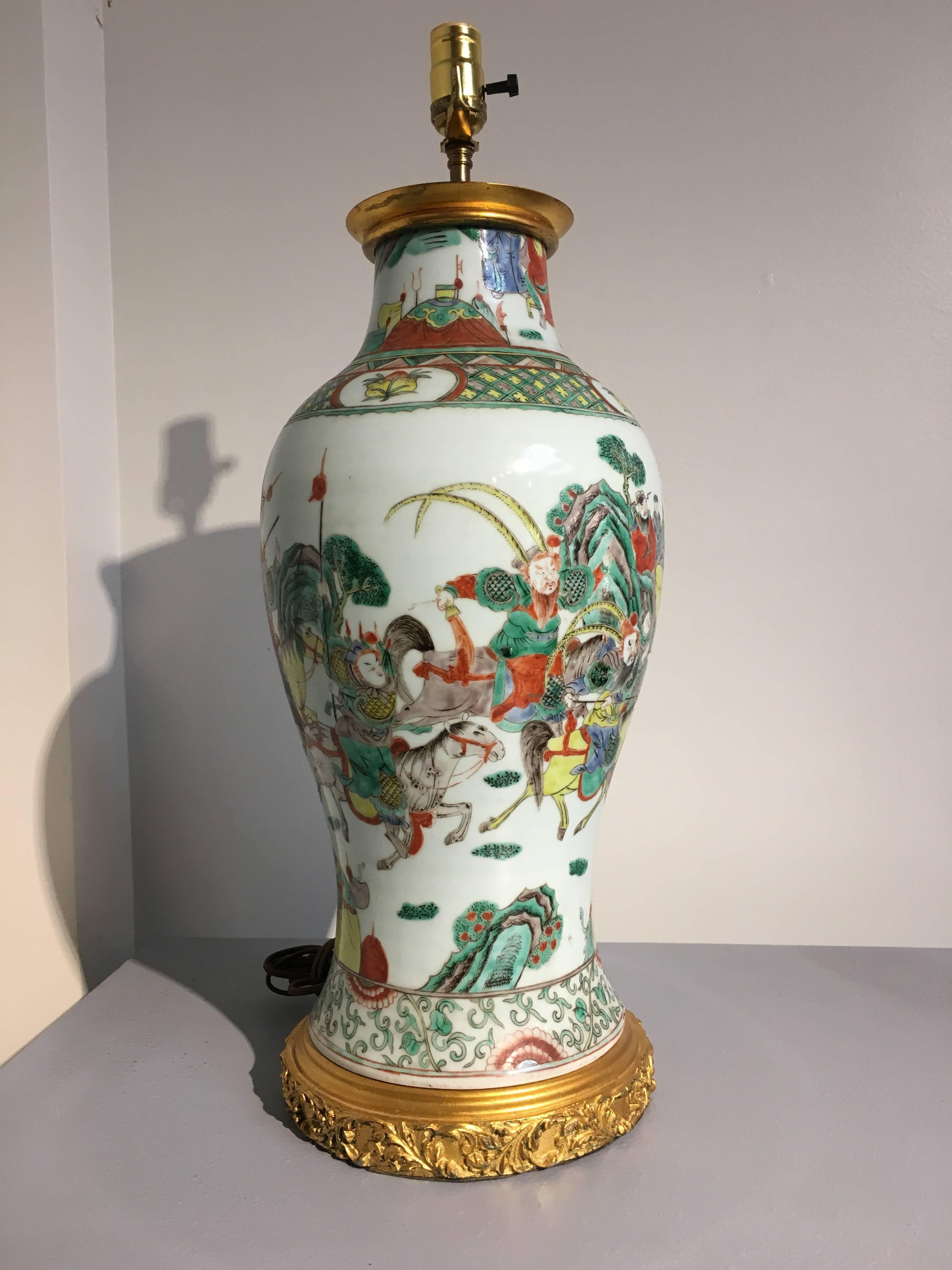 A large Chinese porcelain famille verte battle scene vase fitted with gilt metal mounts and converted into a lamp.
The vase of elegant baluster form. The porcelain body well painted in vibrant famille verte enamels with a lively battle scene