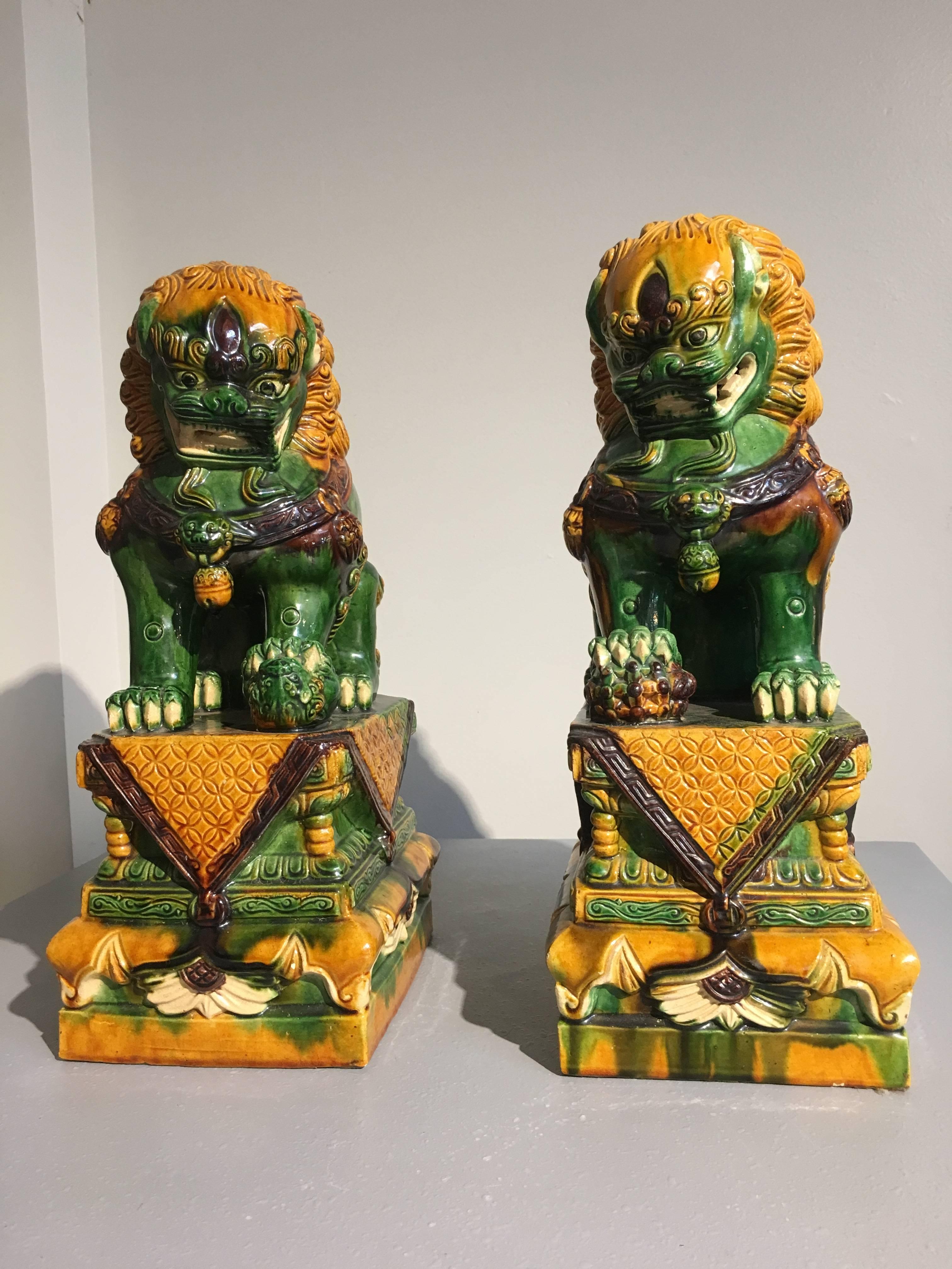 A good pair of vintage Chinese sancai (three color) glazed ceramic foo lions, also called foo dogs. Glazed in wonderful green, yellow and brown, with a nice drip effect, typical of sancai wares. 
Based on guardian lions that grace the entrances to