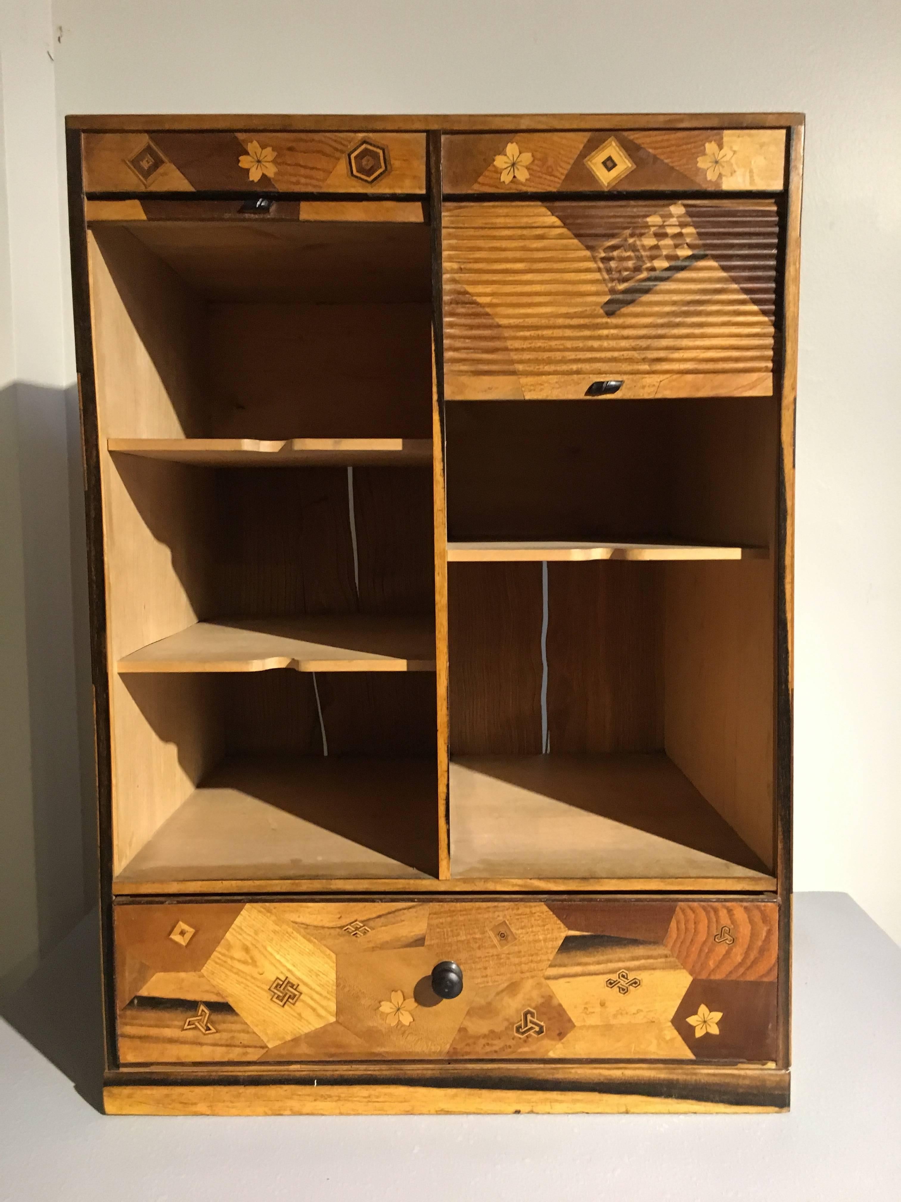 A masterful Japanese Art Deco period marquetry desk hutch with two roll top doors.
The interior fitted with three cubbies on the left, two on the right, with a single drawer to the bottom.
Beautiful marquetry work covers the exterior, including