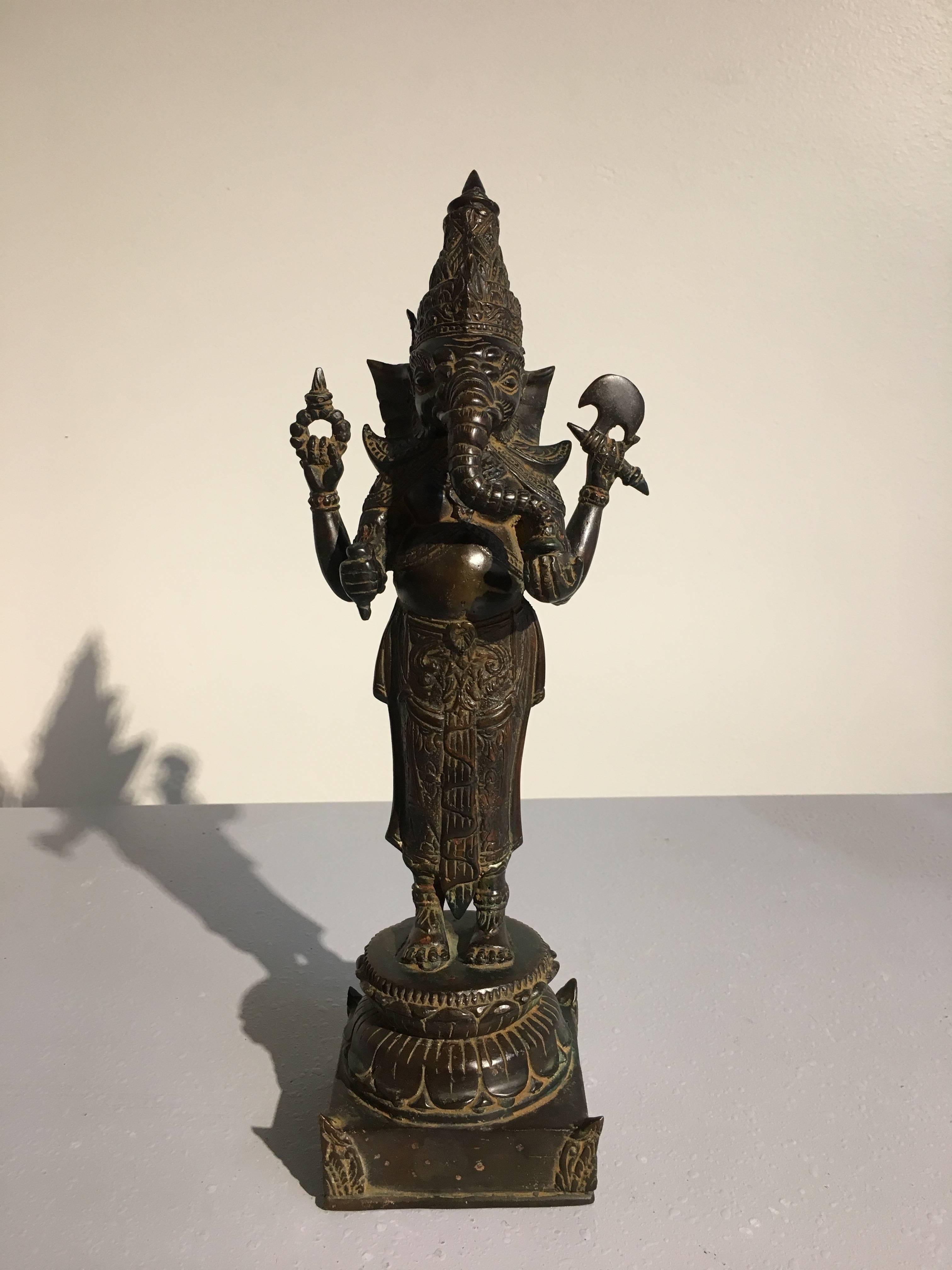 An unusual Khmer style cast bronze image of Ganesh, mid 20th century, Thailand. 

Ganesh, or Ganesha, the beloved elephant headed Hindu god, considered the Remover of Obstacles, is portrayed standing bare chested upon a double lotus pedestal. His