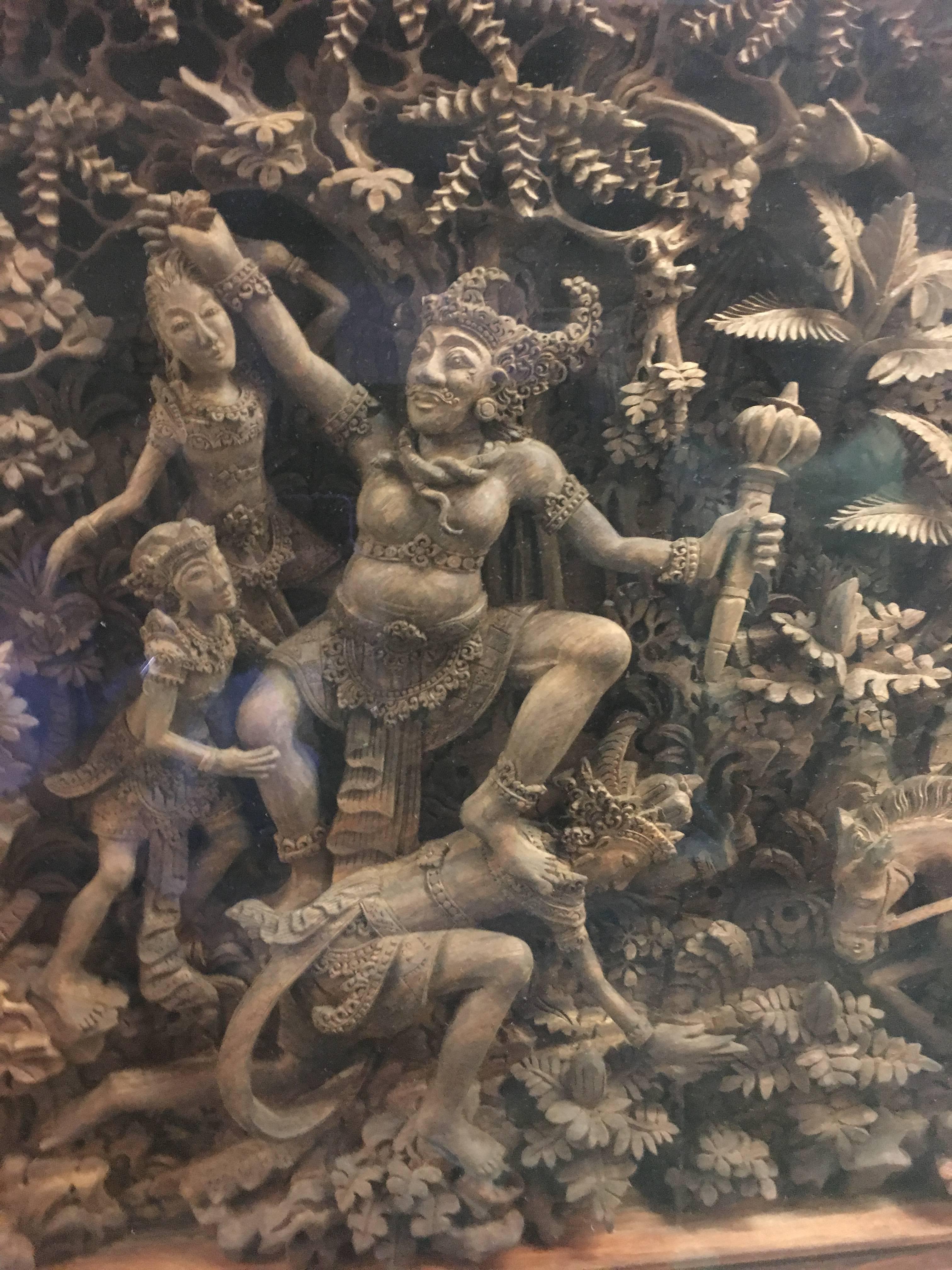 A massive carved teak panel featuring the decisive battle scene in the Hindu epic, the Ramayana, between Prince Rama and the Demon King Ravana. 
The scene is deeply carved in high relief from a single piece of timber. The Demon Ravana is portrayed