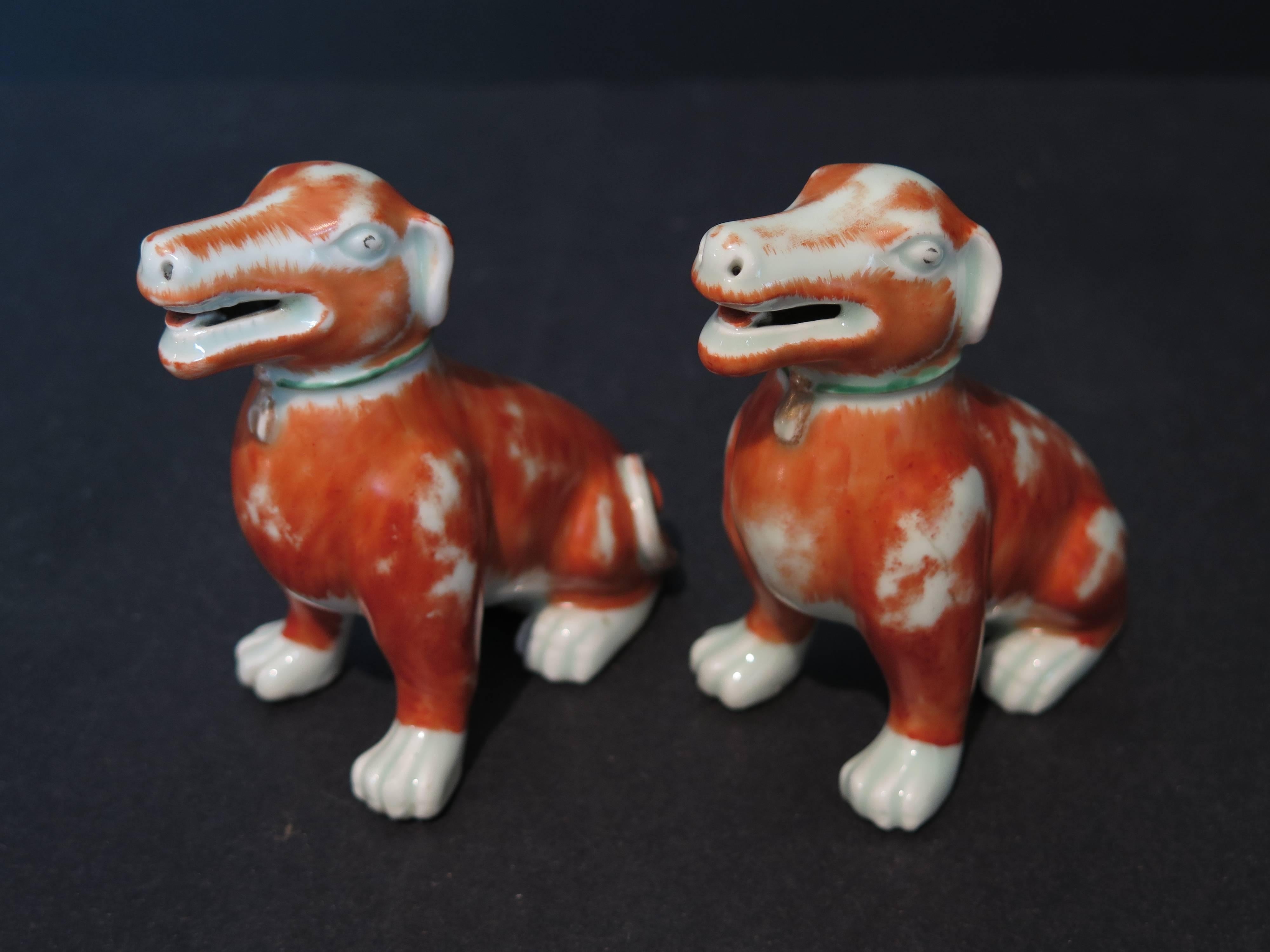 A pair of 18th century Chinese export iron red, smiling, curly-tailed dog figures made of porcelain with green enamel collar and gilt tag. Measures: 4.5