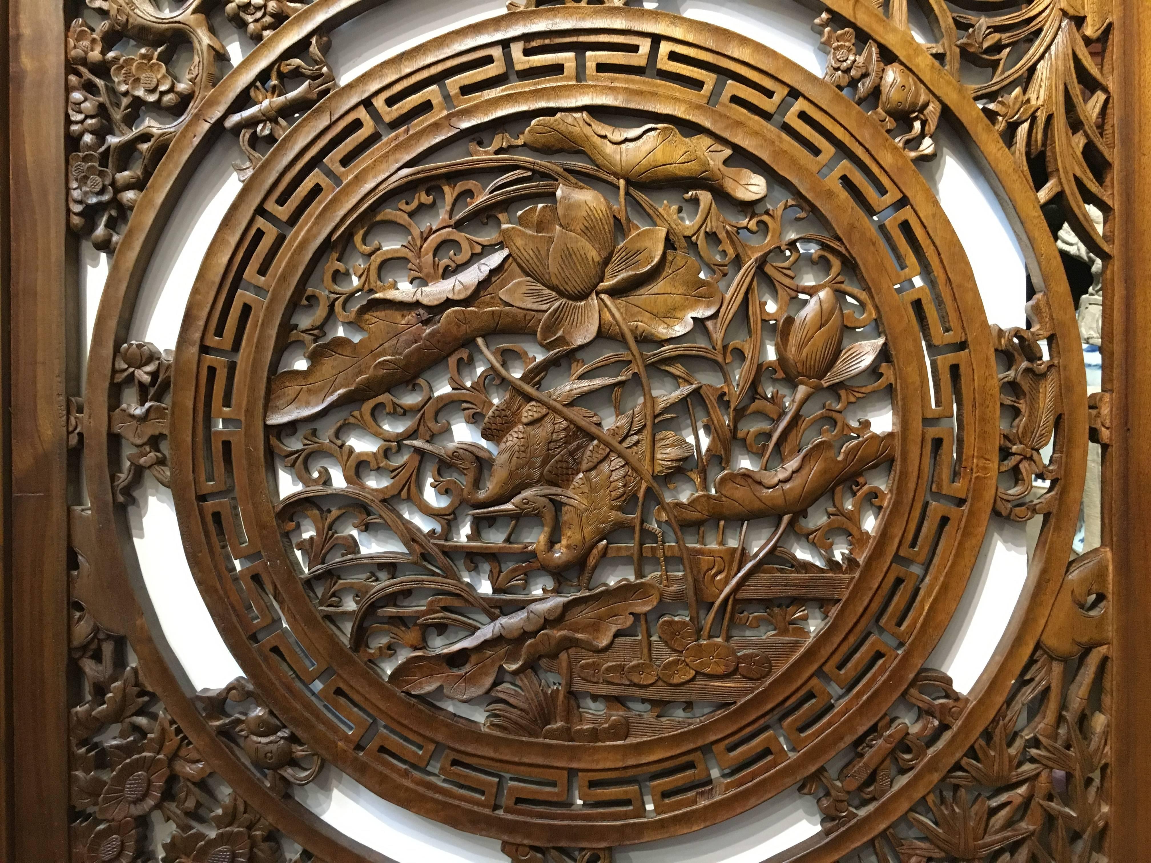 An attractive carved sandalwood Chinese window screen. The central medallion with a design of a pair of heron amongst lotus blossoms, all surrounded by a geometric border and the Eight Daoist Emblems. The corners featuring carved floral groups