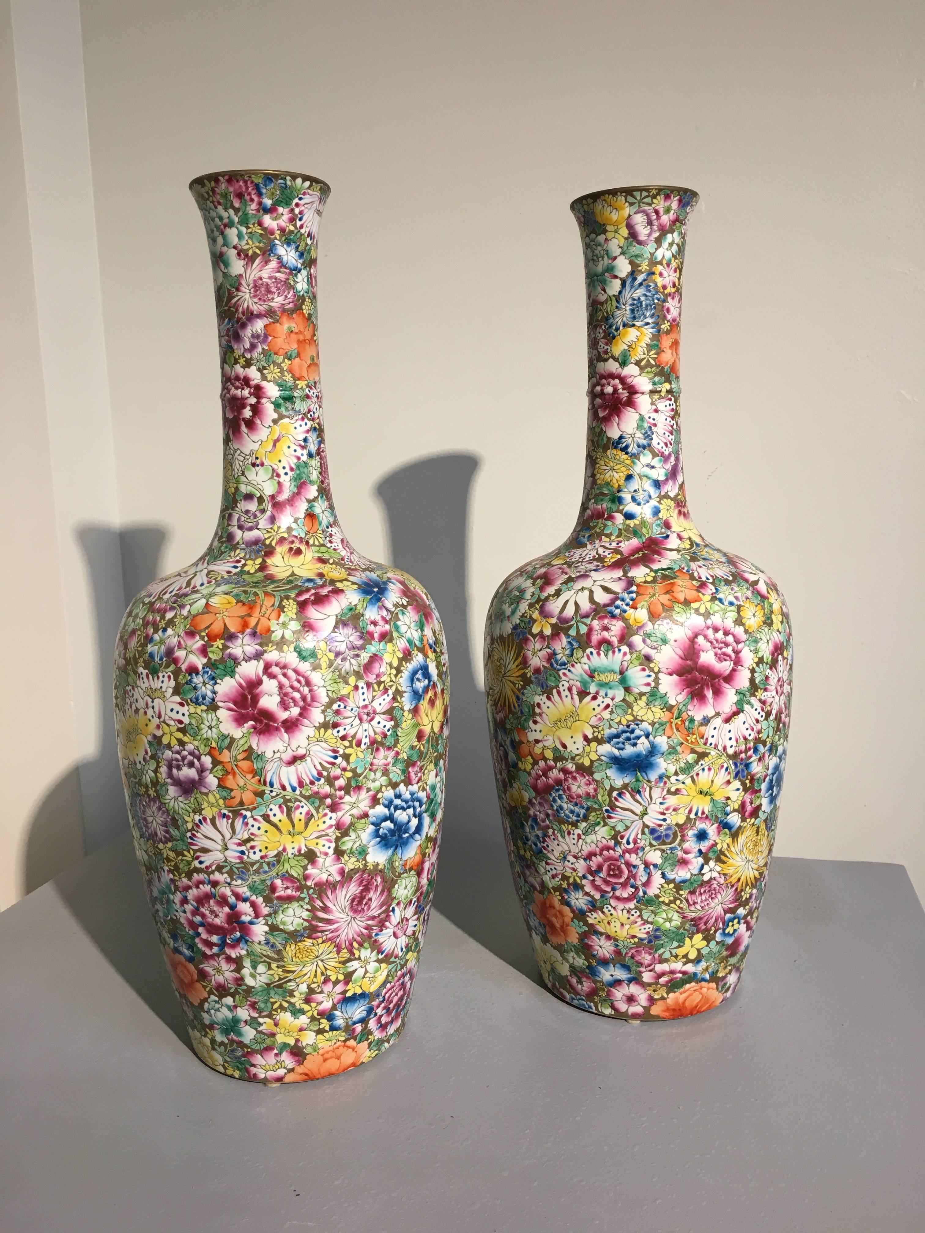 A stunning pair of marked Chinese famille rose enameled millefleurs tall porcelain vases, Republic Period. 
The vases painted in bright and exuberant famille rose enamels in the millefleurs or thousand flowers, pattern upon a gilt ground. Their