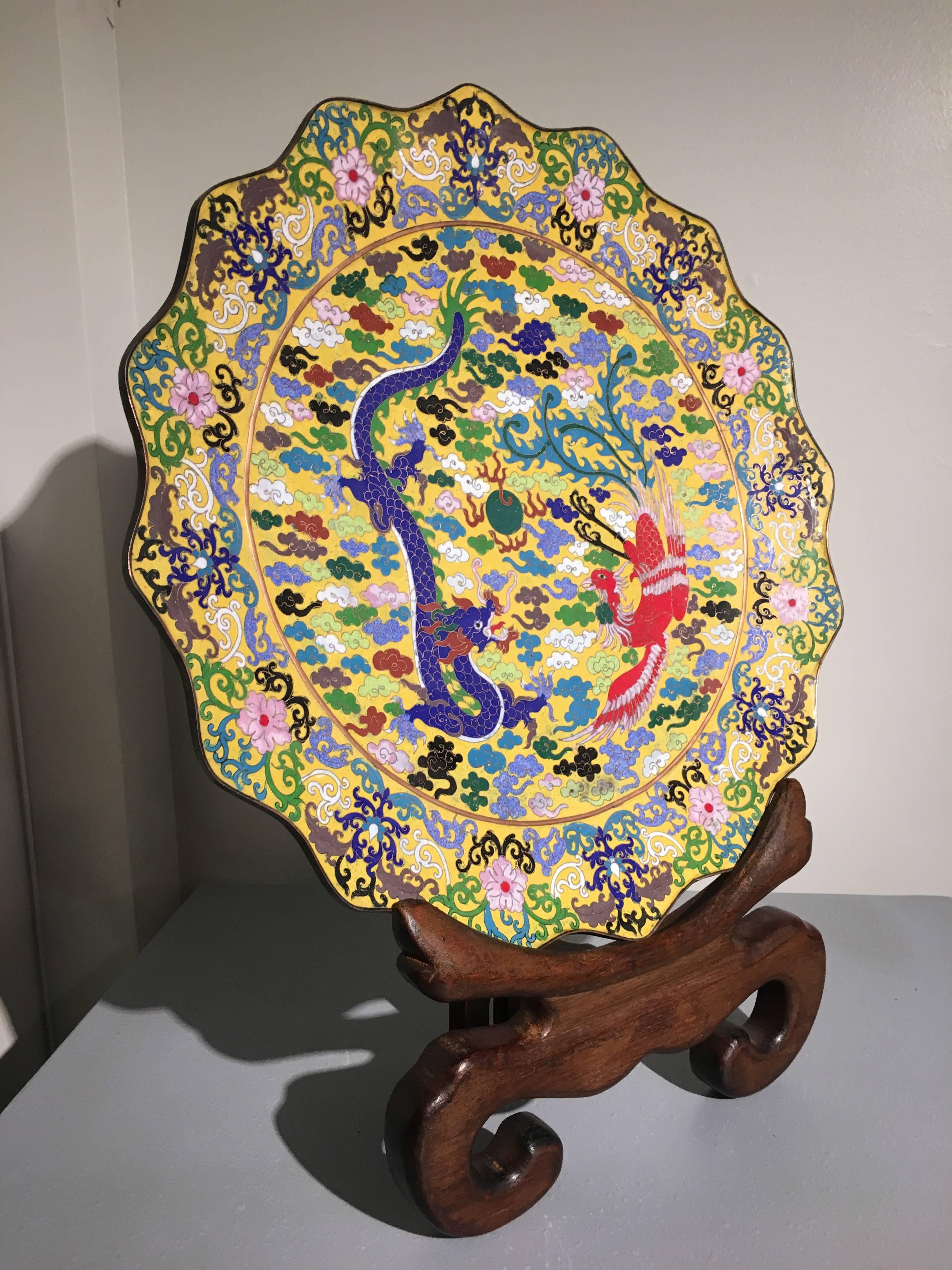 A stunning and impactful large, Chinese Republic period, yellow ground dragon and phoenix marked cloisonné charger.
The charger with a foliate rim and a central decoration of a blue dragon and red phoenix, both in flight amongst stylized clouds,