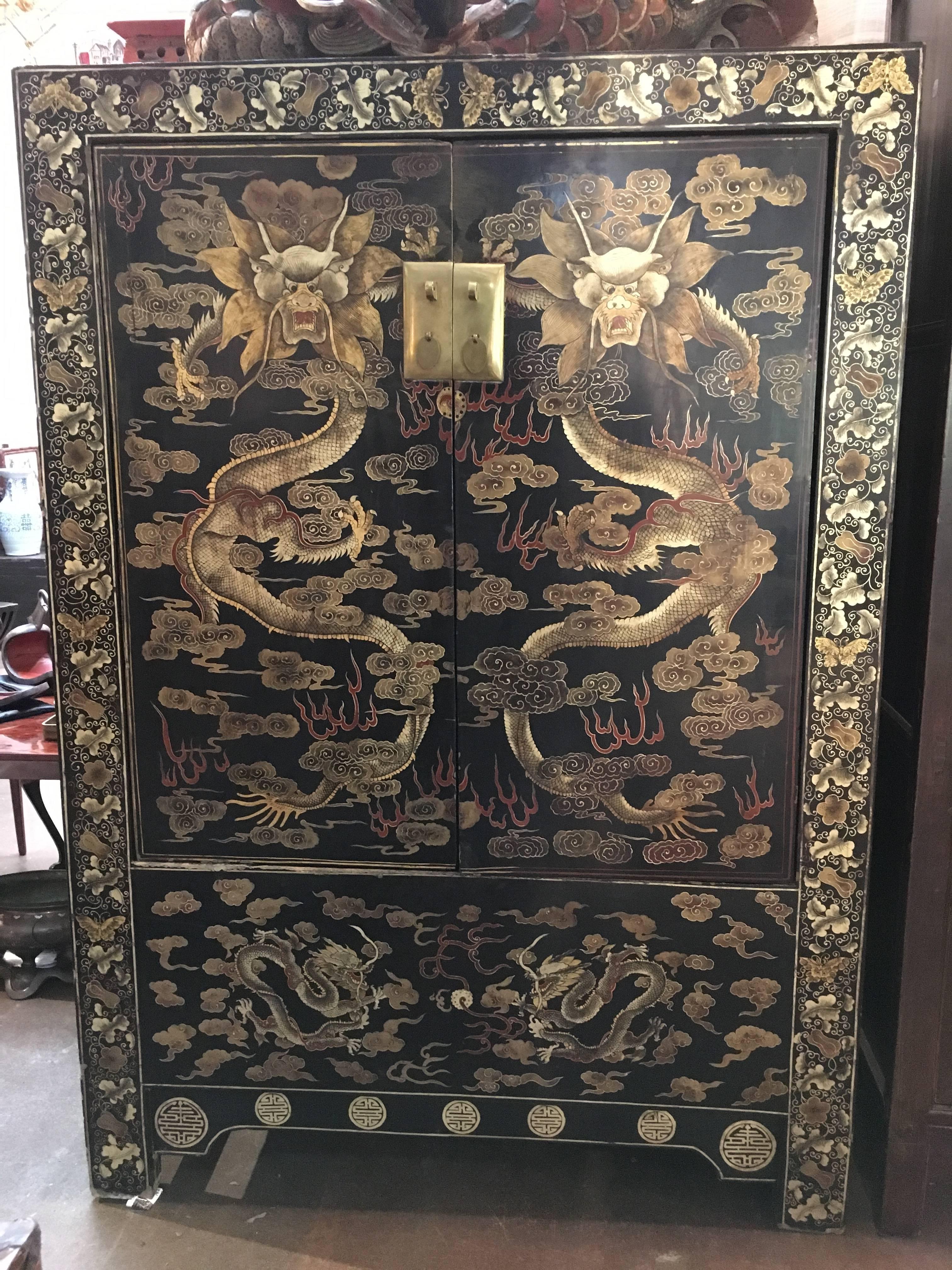 A stunning and powerful Chinese black lacquer cabinet with gilt painted dragons and a large brass lock plate, Qing Dynasty, late 19th century, China. 

The cabinet of generous size with matching proportions. Each door painted with a writhing four