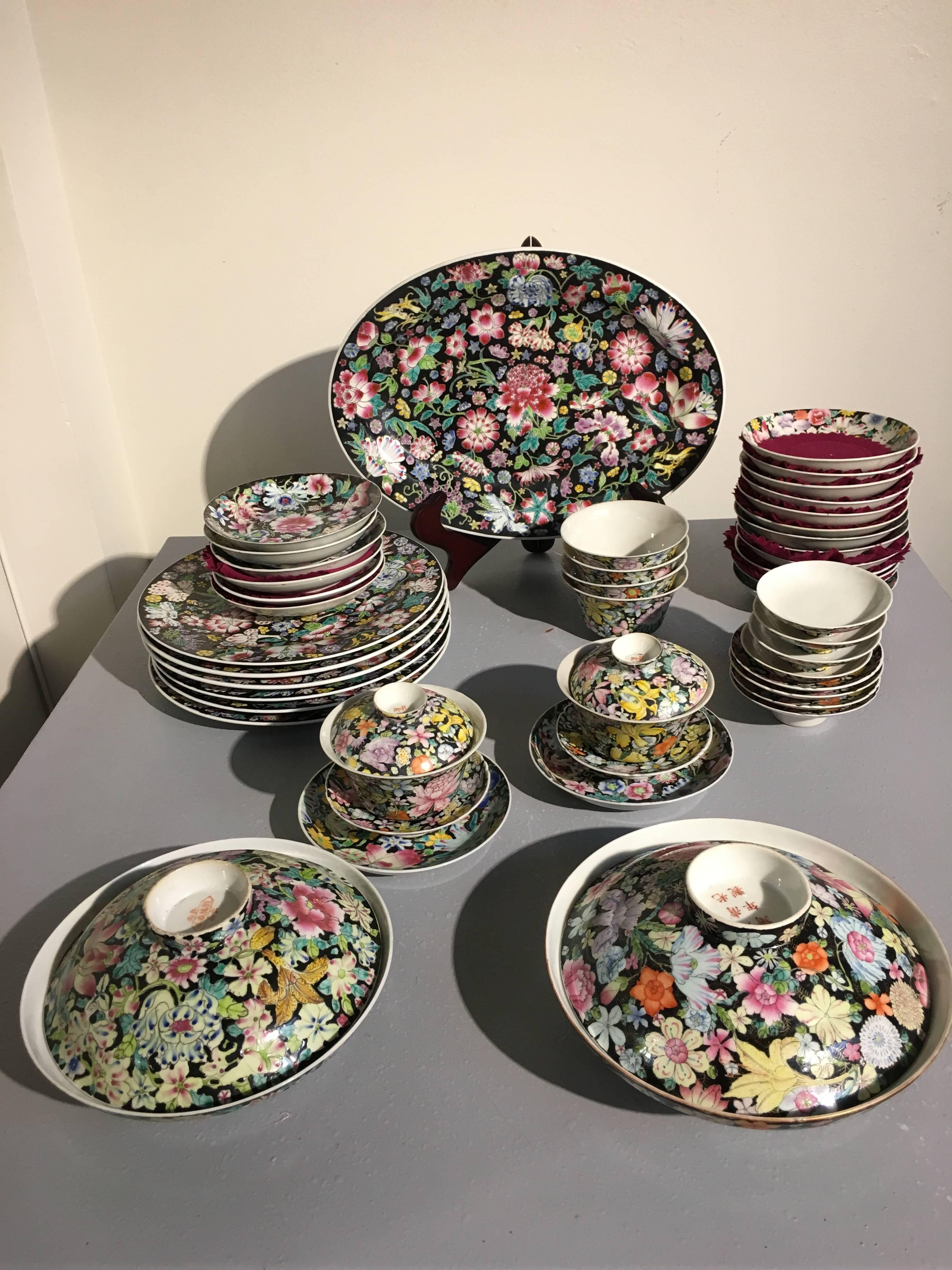 A large assembled set of Chinese porcelain mille fleur wares. The set featuring a full tea service, as well as various plates, cups, and saucers. All piece in the mille fleur, or thousand flowers, pattern, on a black ground. All pieces marked with