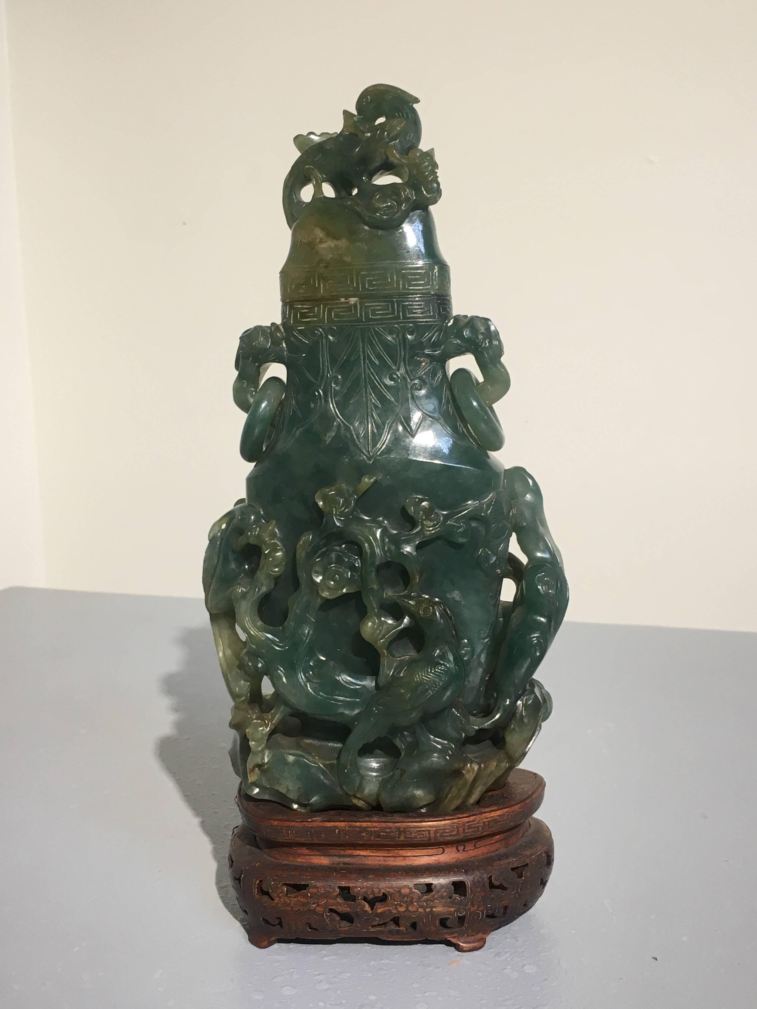 A stunning carved and pierced Chinese jade vase, Qing Dynasty, 19th century. The vase is carved with a design of birds, flowers and trees, each rife with meaning. The dense, heavy jade of a deep, mostly even bluish green color, with small areas of