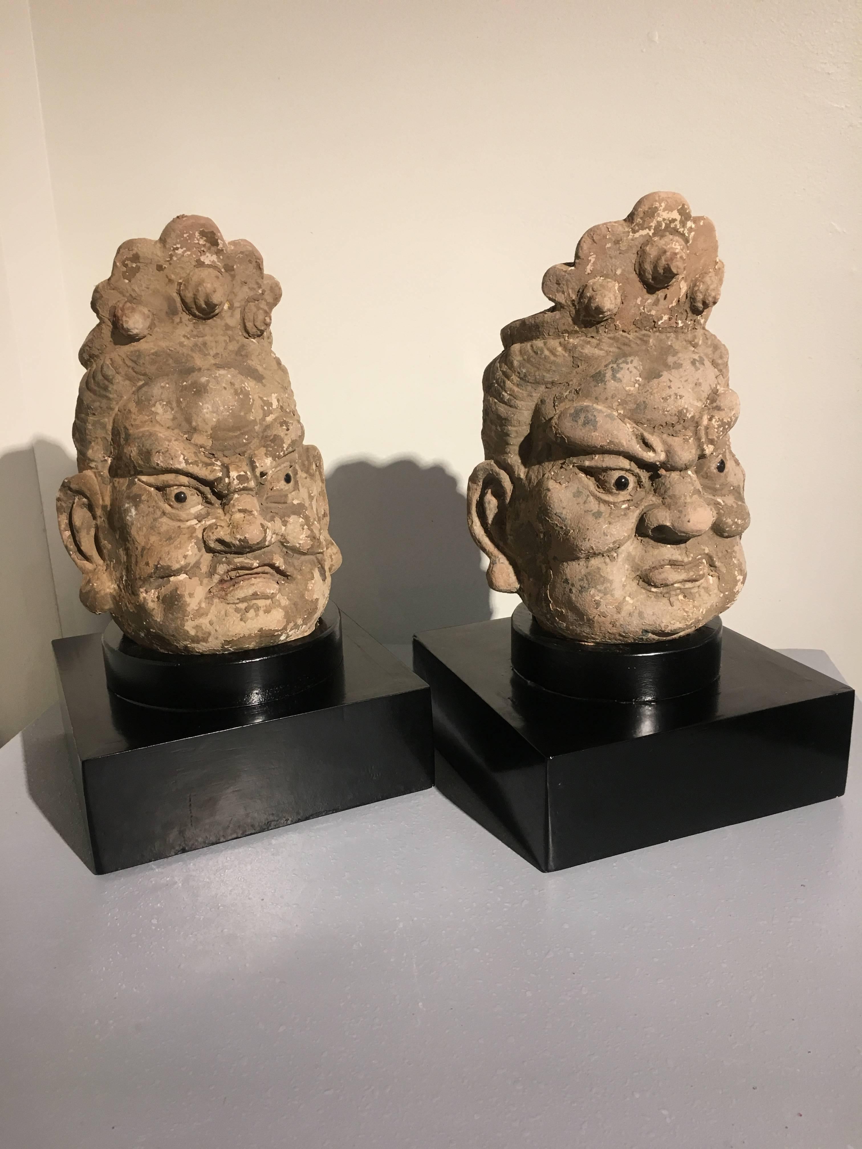 A powerfully sculpted pair of Chinese stucco heads of guardian figures, called lokapalas, Yuan to Ming Dynasty, circa 14th century.  

Originally part of larger than life sized figures of dvarapala (gate or door guardians), these fearsome warriors