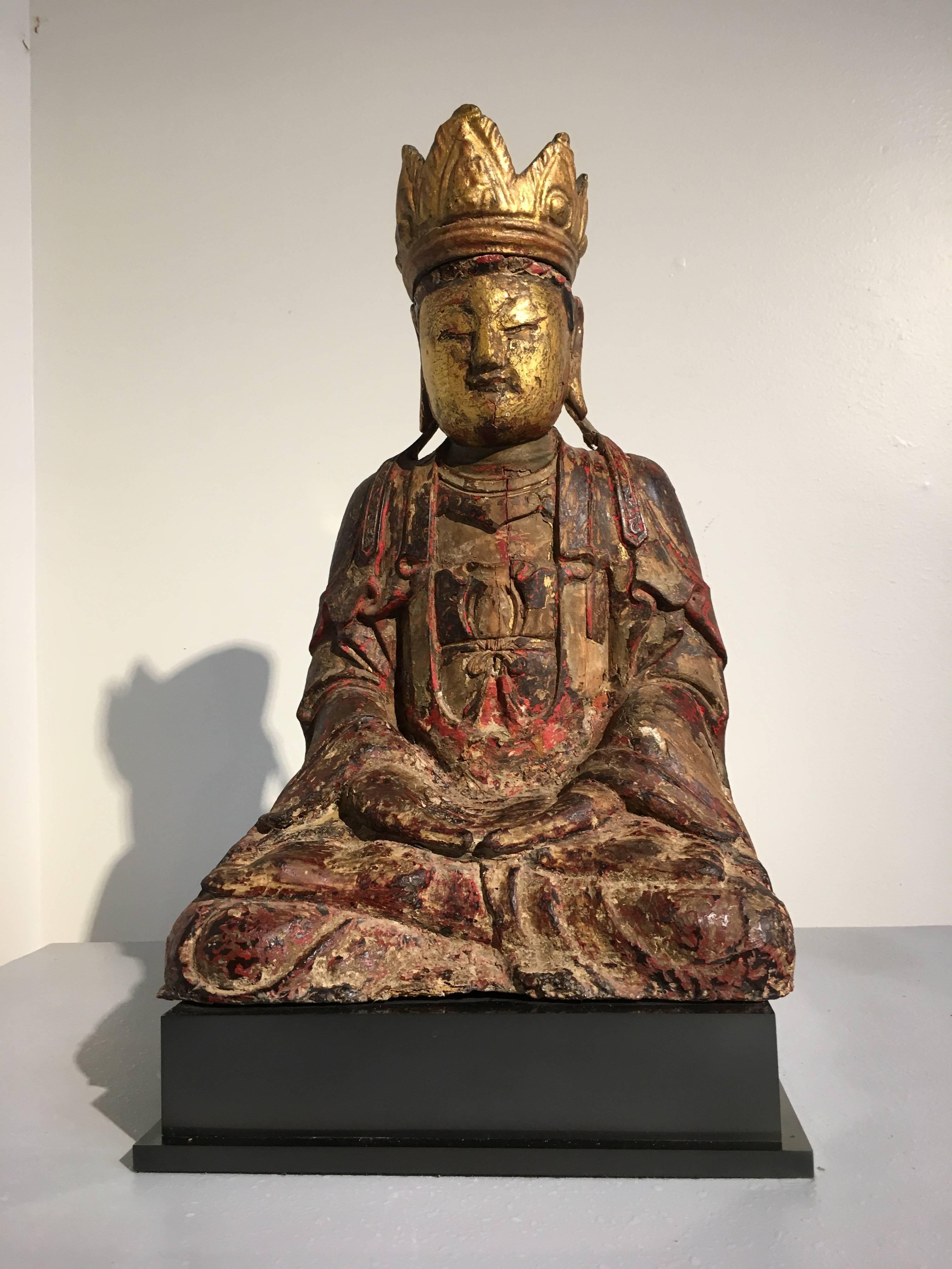 Une belle et sereine figure en bois sculpté de la dynastie chinoise Ming représentant le Bouddha Amitayus, le Bouddha de la longue vie, et une forme du Bouddha Amitabha. Il est assis en dhyanassana, vêtu de robes amples et orné d'une couronne à cinq