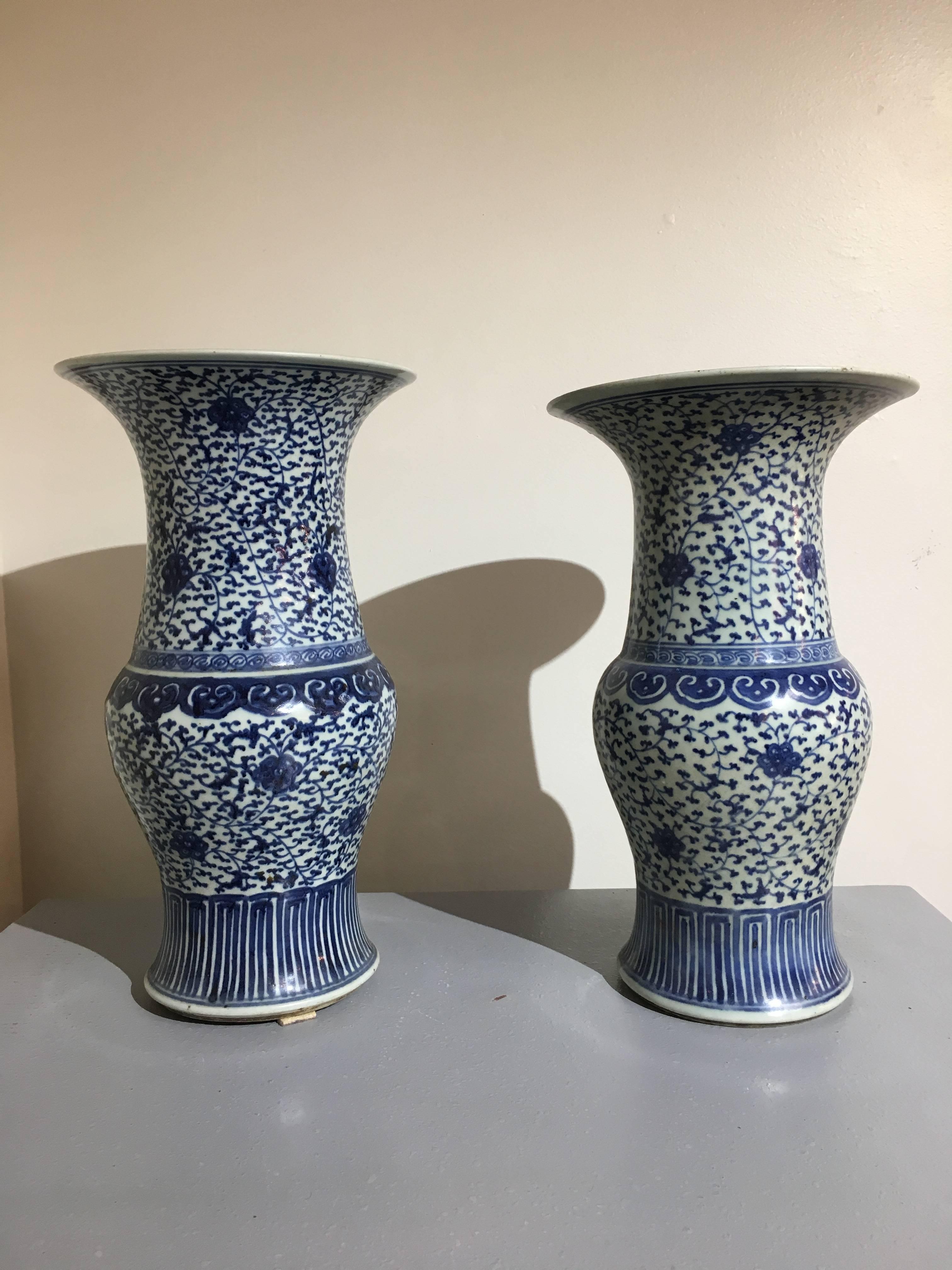 An elegant pair of Chinese blue and white yen yen vases, also called phoenix tail vases. The bodies of baluster form, with wide necks that end in dramatic flaring mouths. Decorated in underglaze blue in a scrolling floral and foliate motif. The