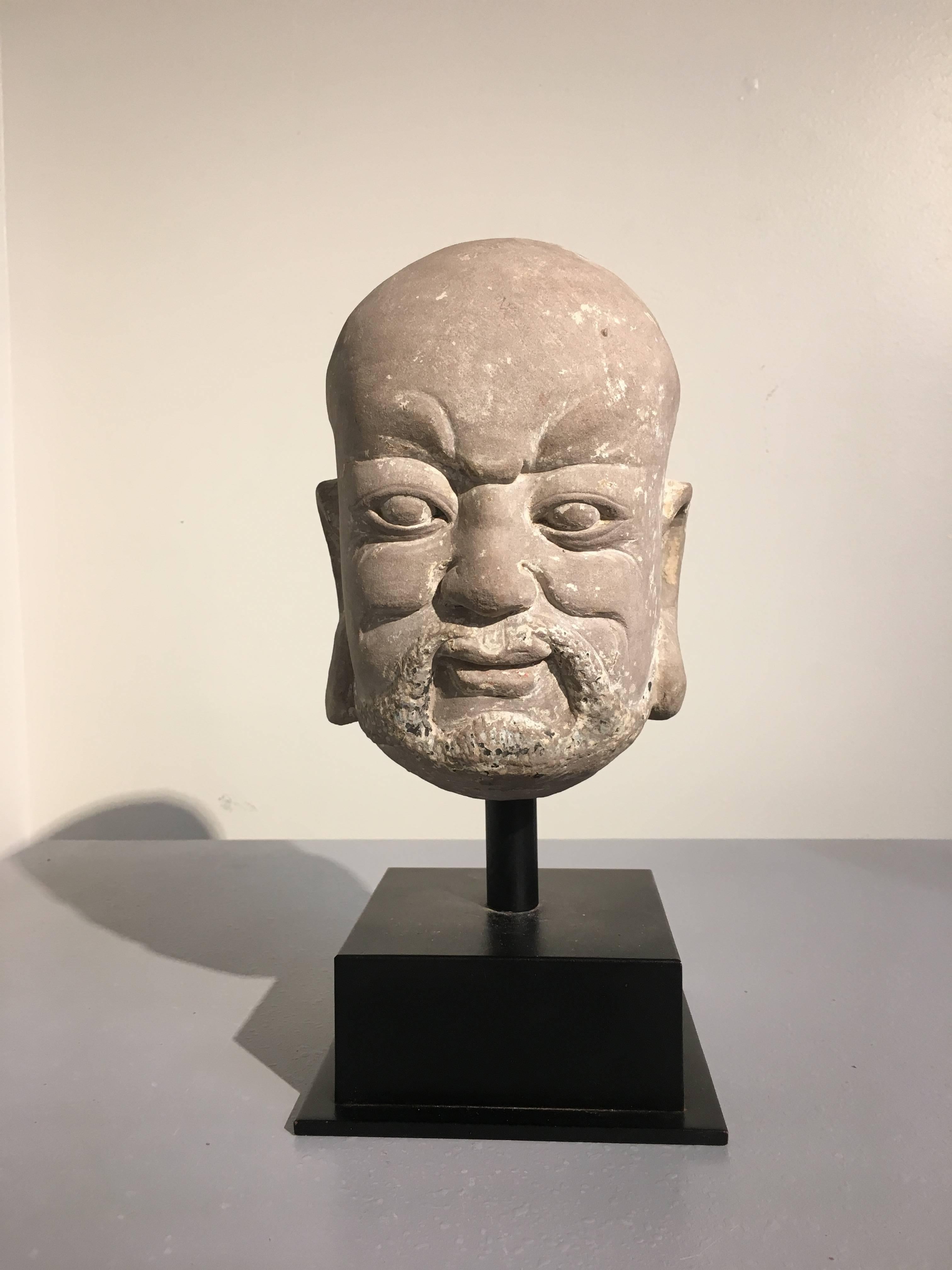 A well carved and expressive limestone head of a luohan, Yuan Dynasty (1271-1368), China. 
Luohan (lohan), also called arhats, were the original disciples of the Buddha and are revered figures in Buddhism. Chinese Buddhism names 18 original luohan,