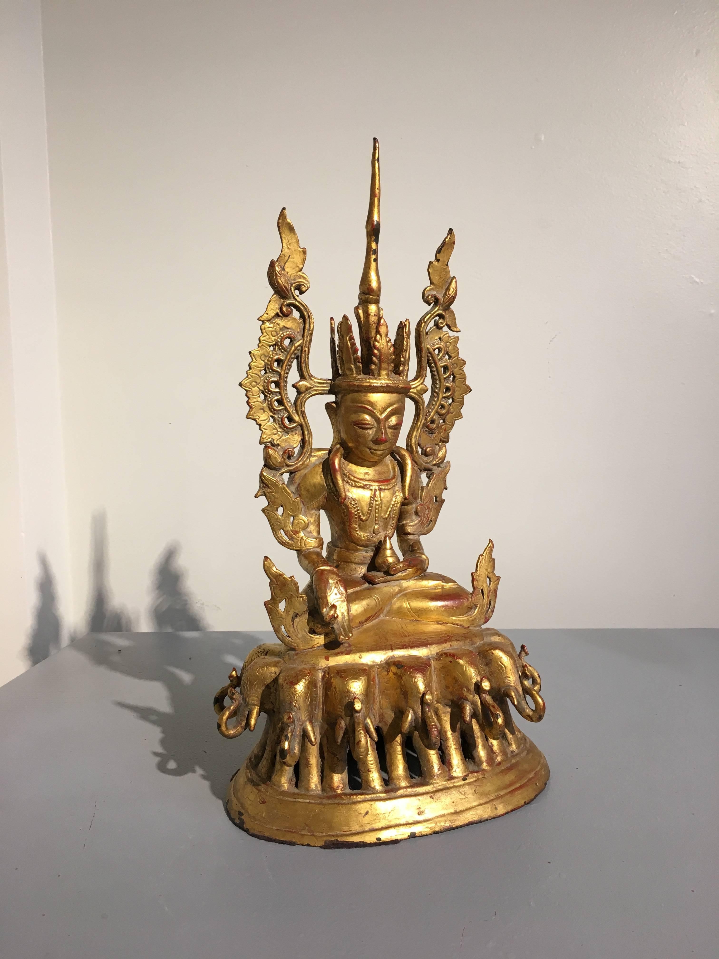 An unusual 18th century Burmese Arakan style red lacquered and richly gilt cast bronze figure of the Crowned Medicine Buddha, commonly referred to as Bhaishajyaguru.
The Supreme Healer is portrayed seated in vajrasana (full lotus position) upon a