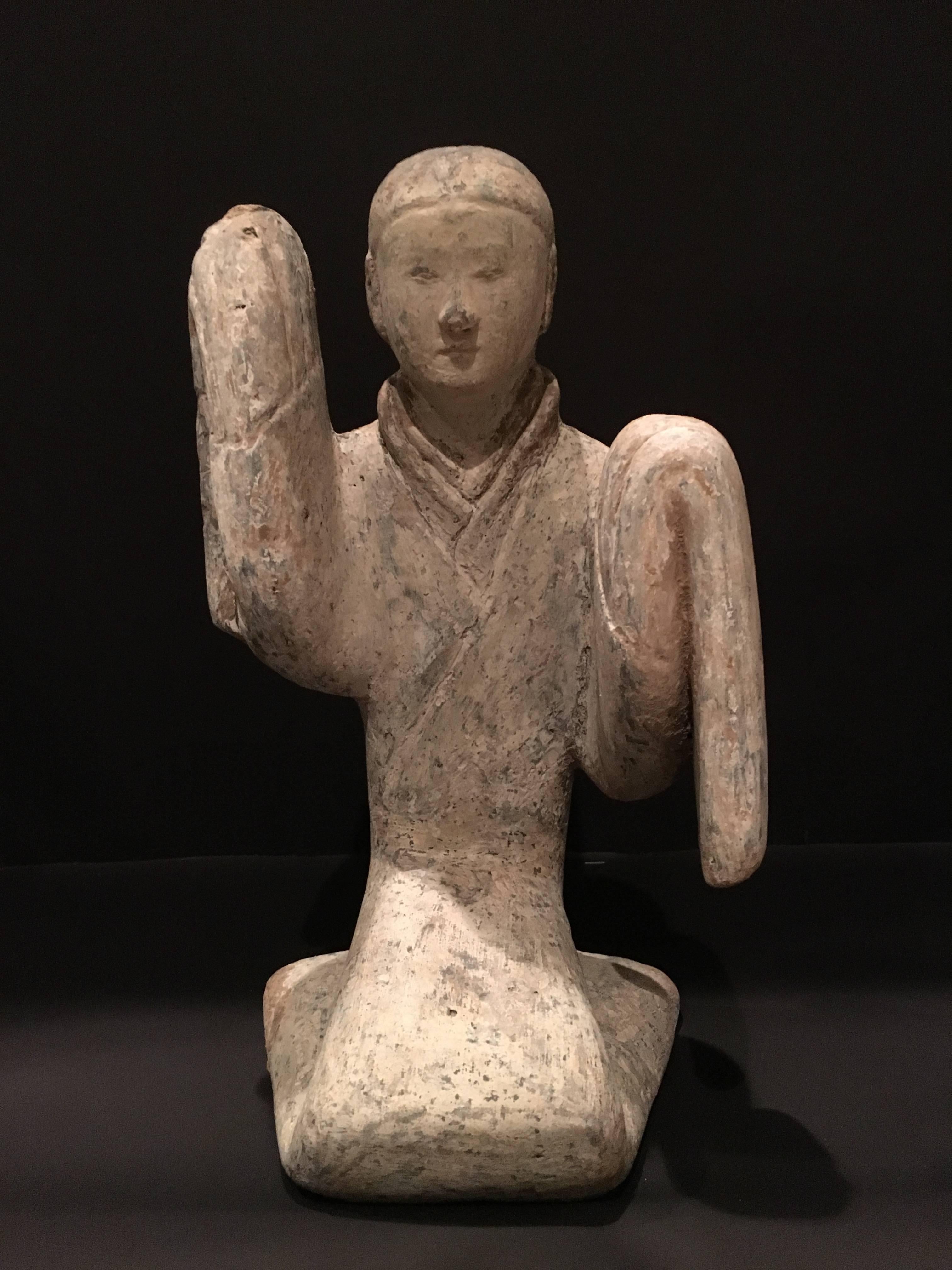 A stunningly quiet and elegant Western Han dynasty (206 BCE - 9 CE) high fired gray pottery figure of a female long sleeved dancer. 
The young dancer is portrayed in a moment of quiet contemplation just before she starts her dance. She sits