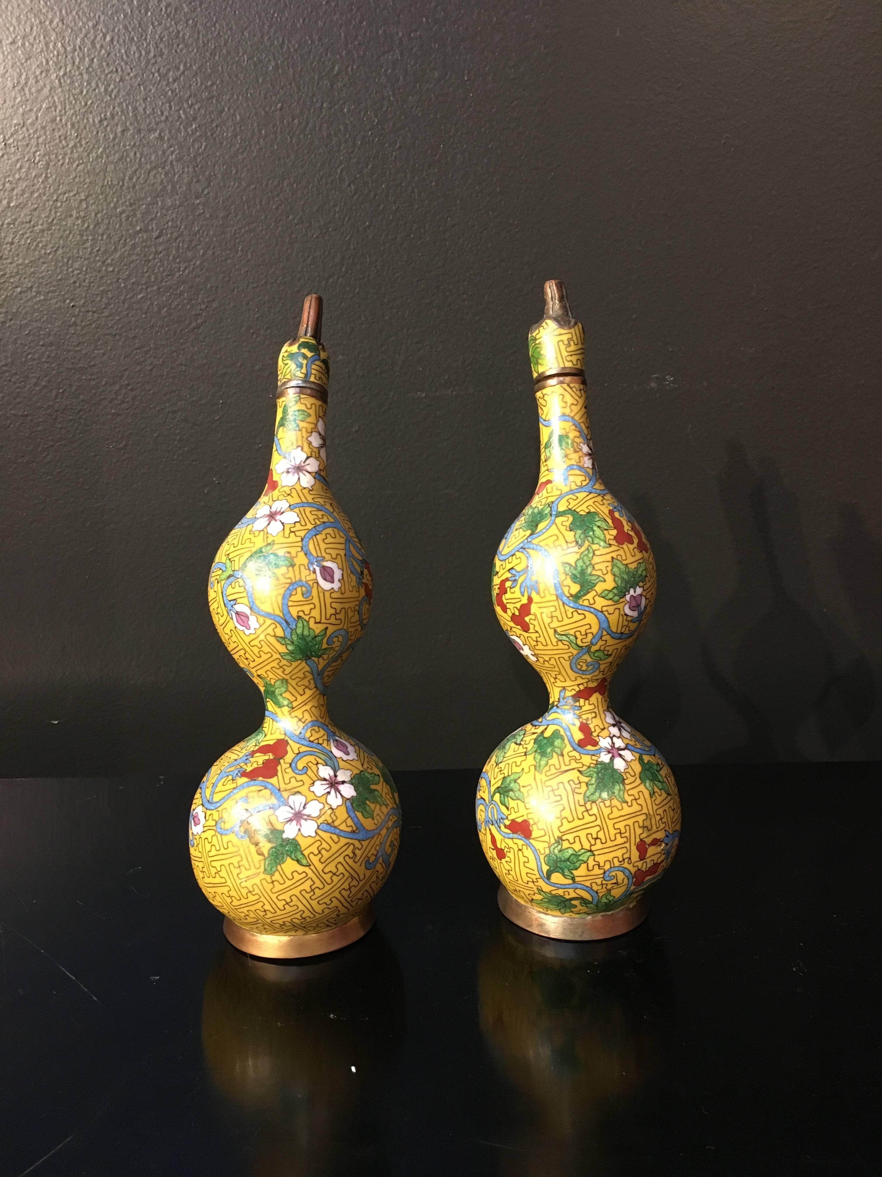 A delightful pair of Chinese yellow ground cloisonné double gourd decorative bottles or vases, Republic Period, early 20th century. 

Of double gourd form, with removable stoppers, the bottles or vases are decorated with a scrolling flowering vine
