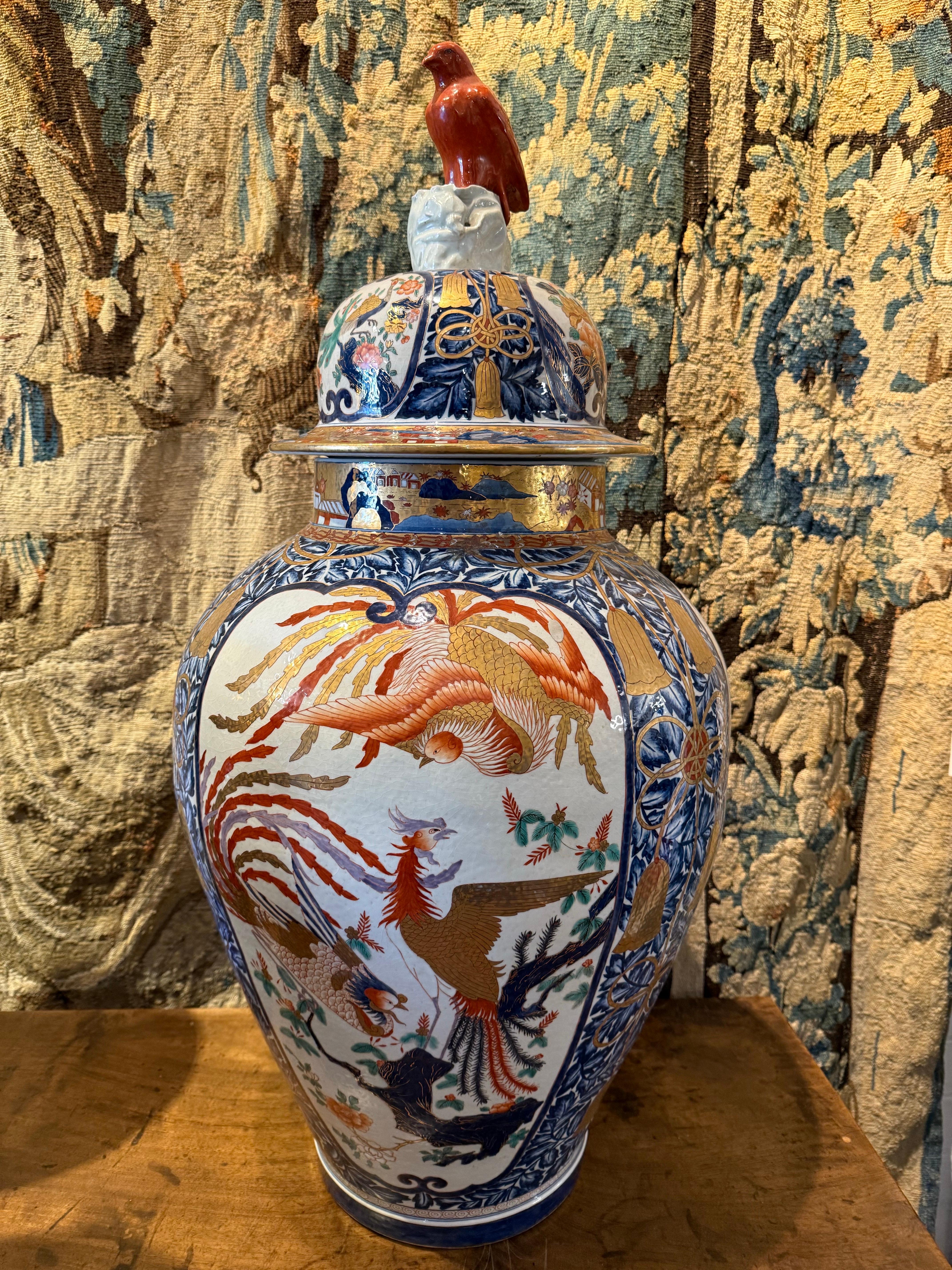 Substantiel vase balustre japonais Imari avec couvercle, début du 20e siècle

Description :
Le vase balustre avec un couvercle bombé surmonté d'un oiseau perché dans un ton de terre cuite, trois cartouches sur le dôme avec chacun des scènes de piafs