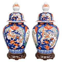 Paire de vases vintage en porcelaine de style Imari, munis d'un couvercle et posés sur des socles en bois