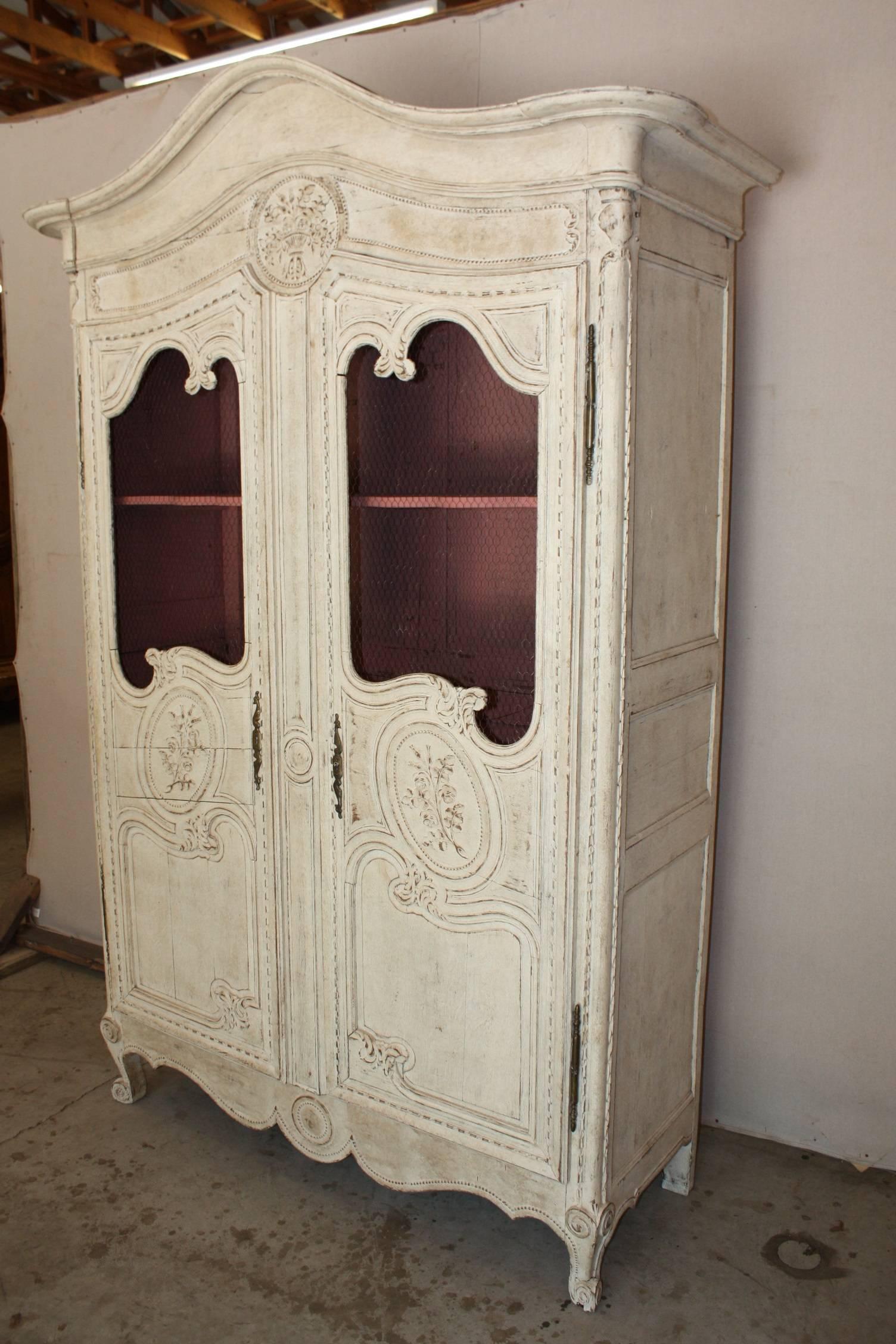 19th century French hand-carved and painted Louis XV armoire with chicken wire doors. This piece is carved with flowers has two shelves and a painted pink interior.