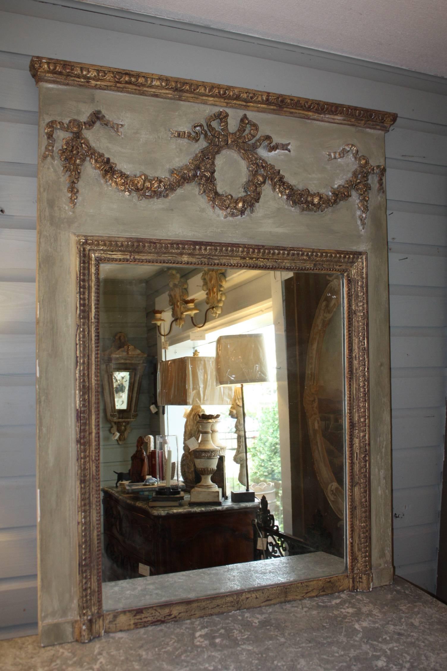 Beautiful 19th century French trumeau mirror painted in a light green/gray with gilded swag and ribbons.