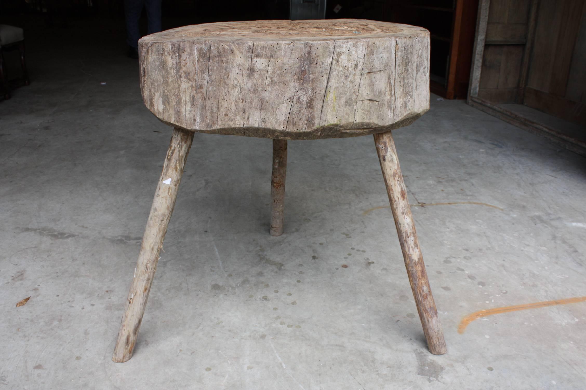 Primitive antique butcher block table with three branch form legs.
