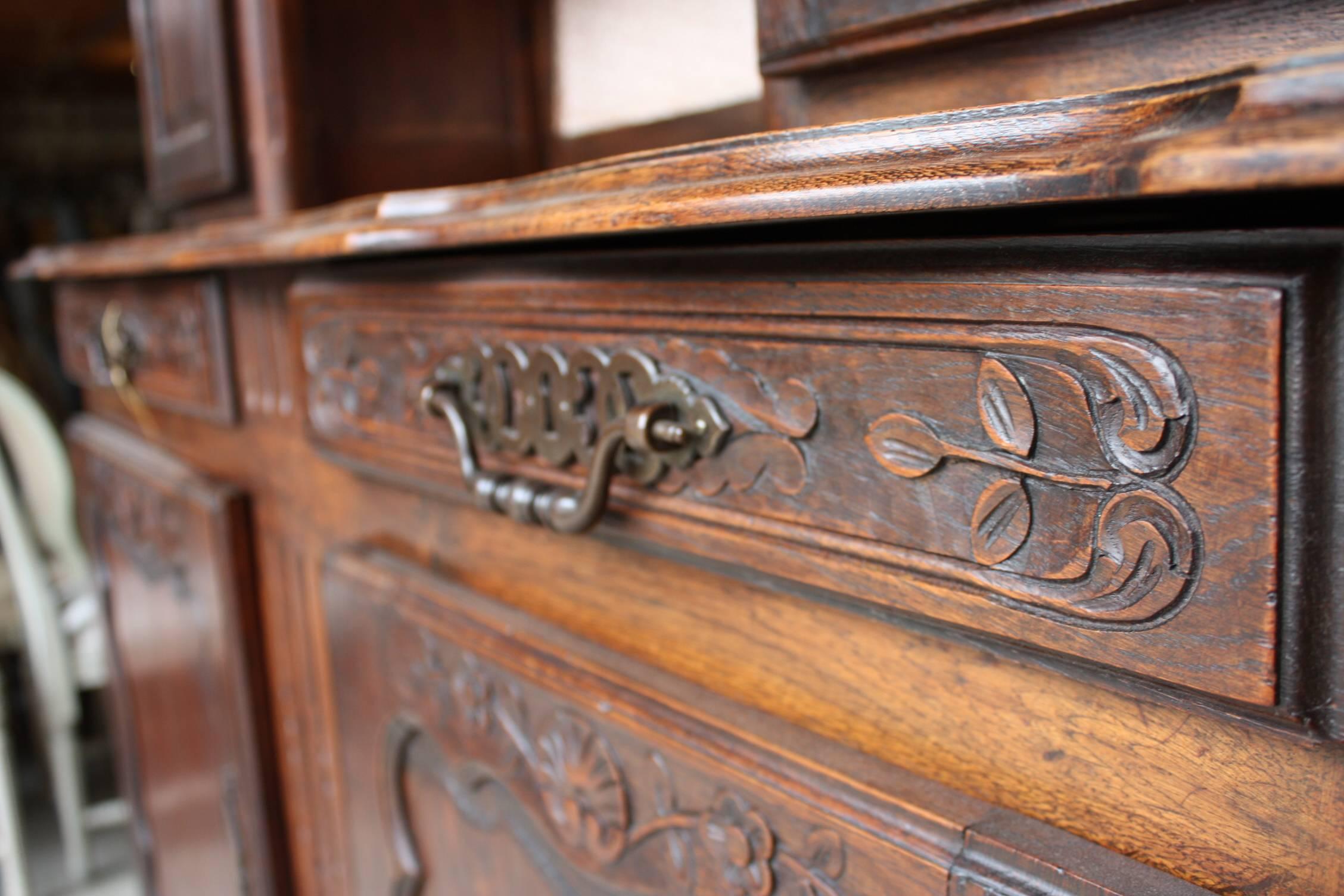 A fine Louis XV period vassellier in walnut, composed of a three-tier plate-rack with cornice and frieze, resting atop an Enfilade with two doors and two sliding drawers, each with fixtures and carved designs. The entire piece sits on a shaped apron