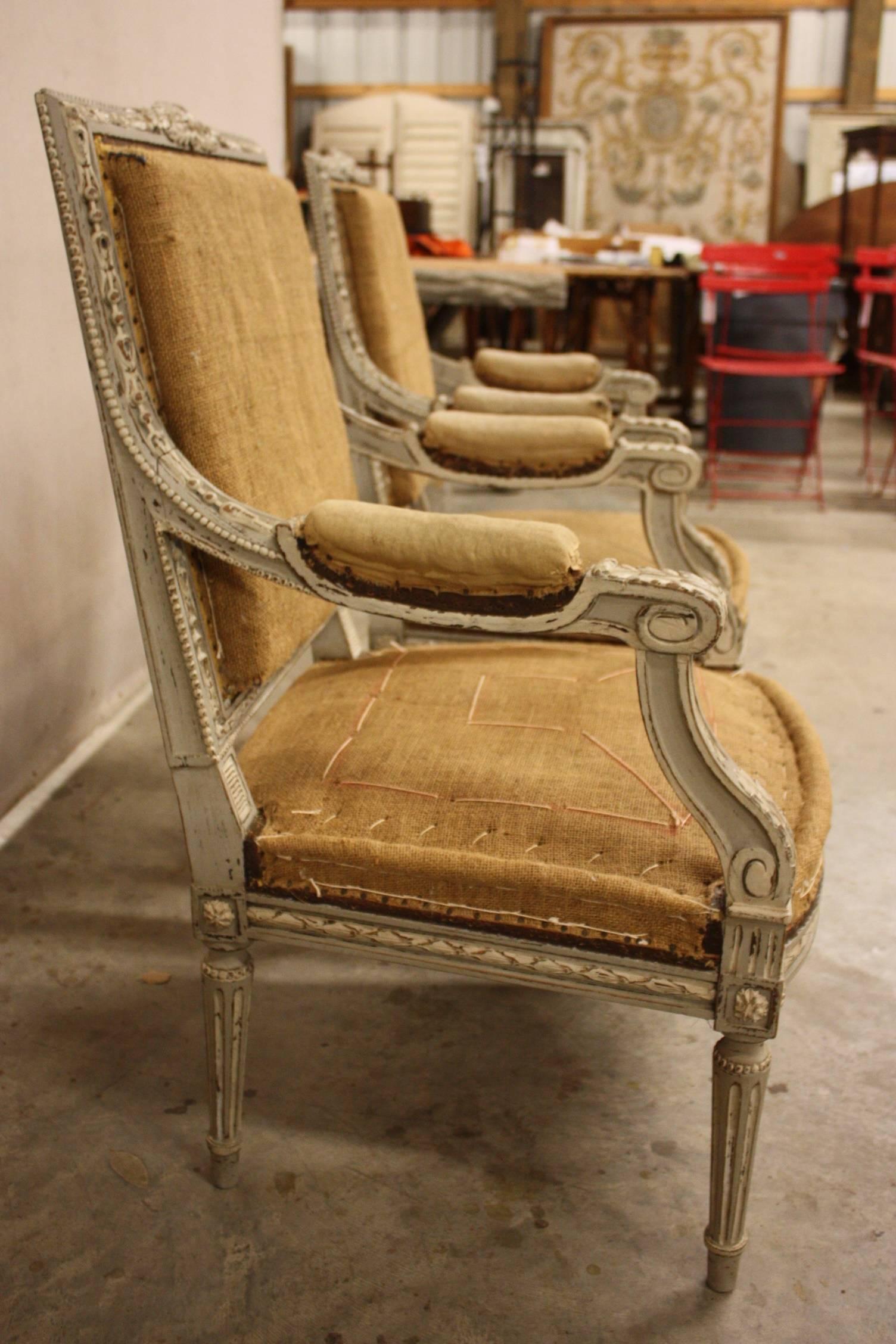 Pair of armchairs, having distressed painted finish, each with square back, padded elbow rests, back and crown seat with nailheads, raised on round fluted legs.