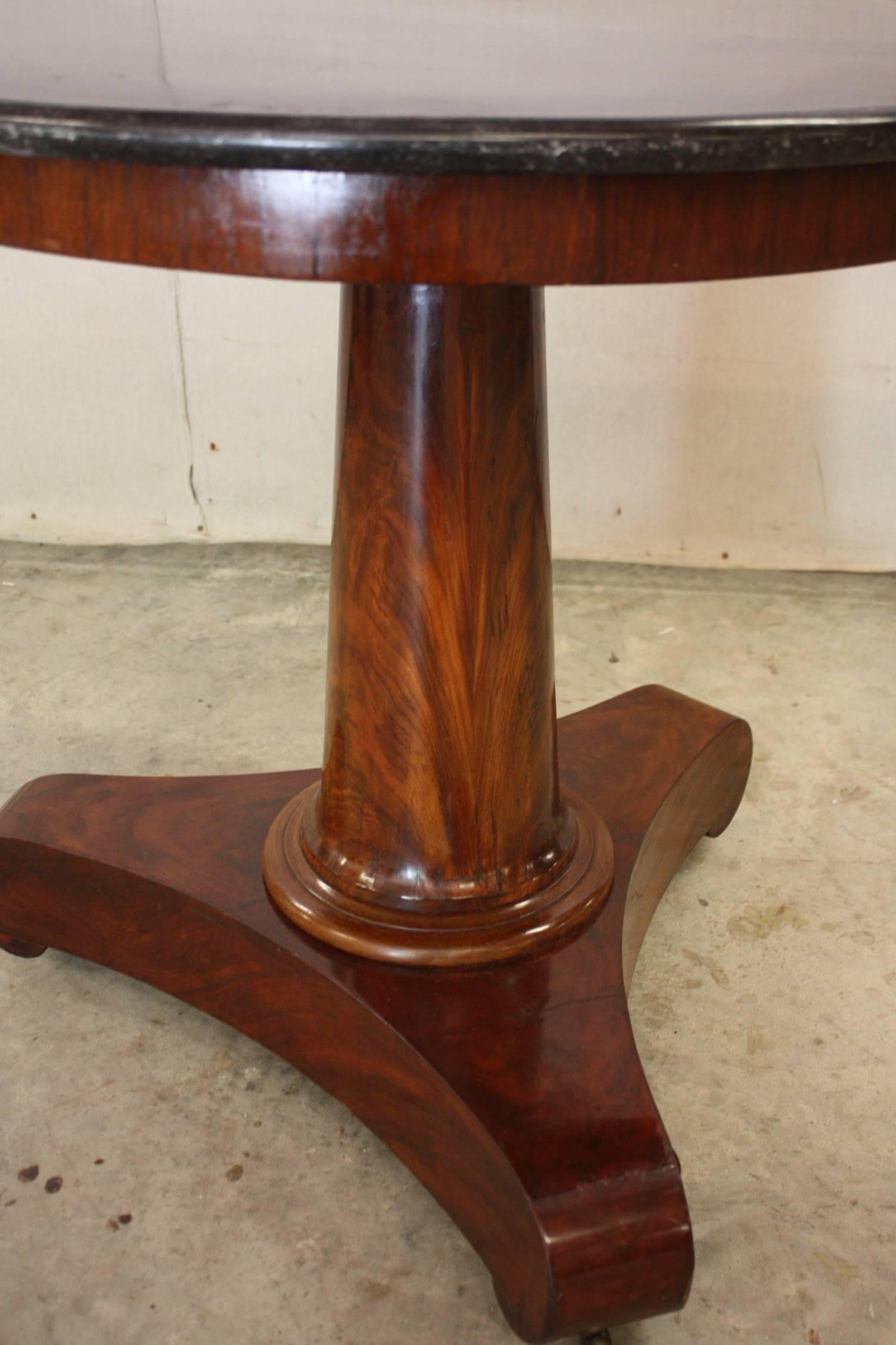 A French Empire style small pedestal table or gueridon made of red mahogany with a decorative brass casters and topped with a round black marble. Quite a lovely table with lots of character. Perfect for a side table or even a centre table.