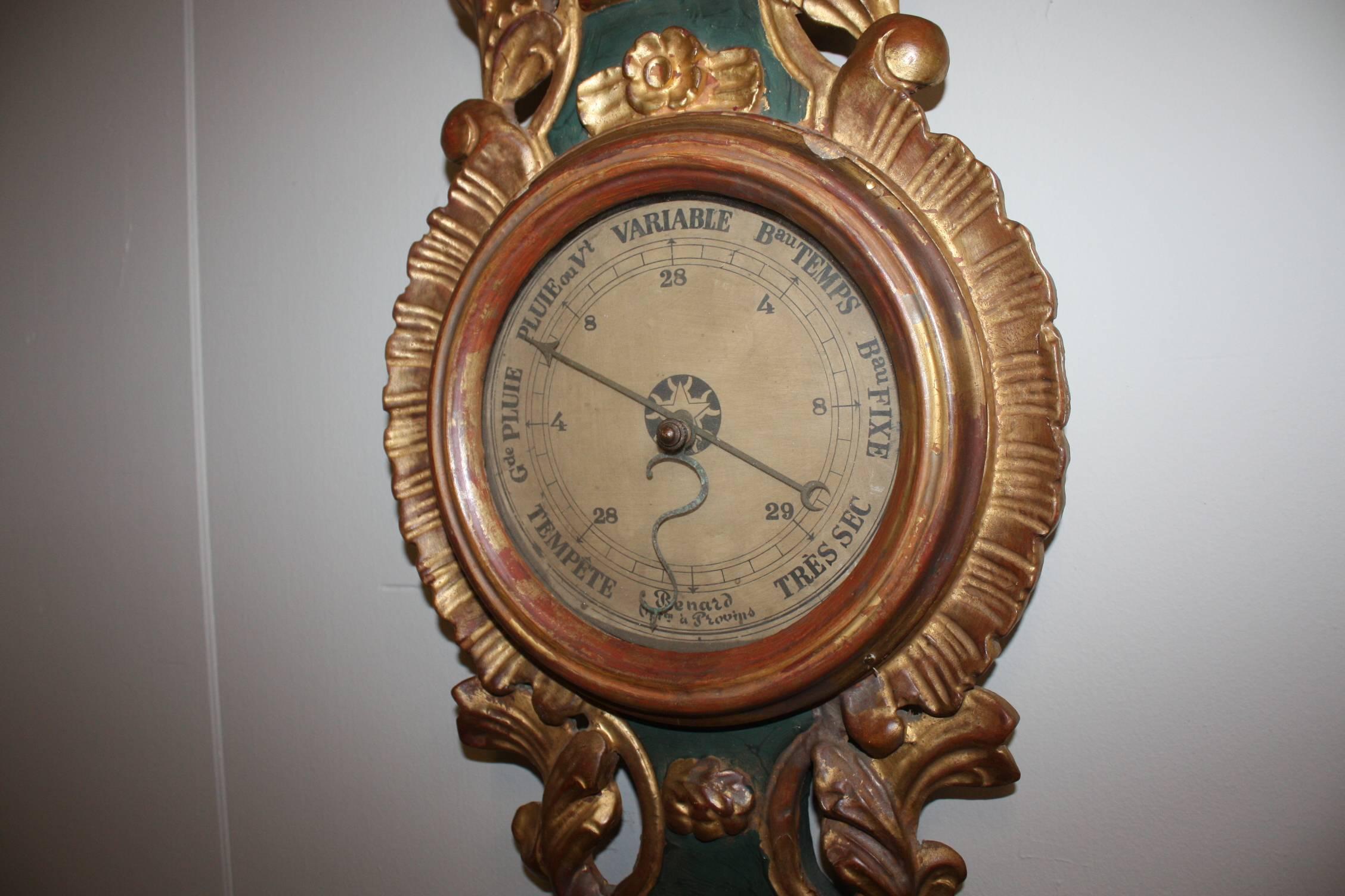 This French Louis XVI style barometer and thermometer features an exquisite carved giltwood crest with delicate foliage motifs. Below the crest, the thermometer, encompassed in a green painted body, sits atop the round barometer. This French