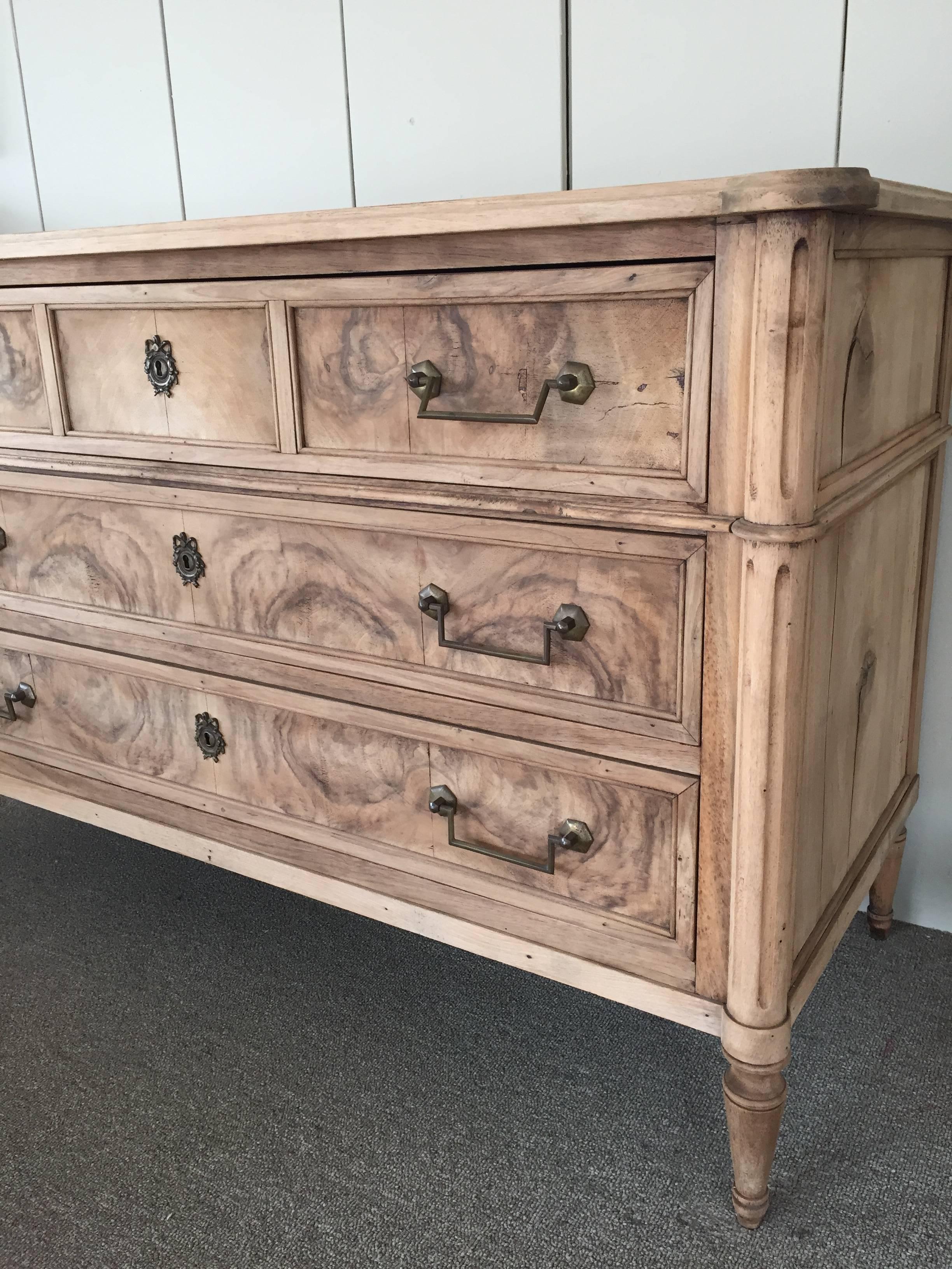 Bleached walnut commode or chest of drawers, having three drawer's facades and supported on curved and fluted stiles sitting on turned toupee feet.