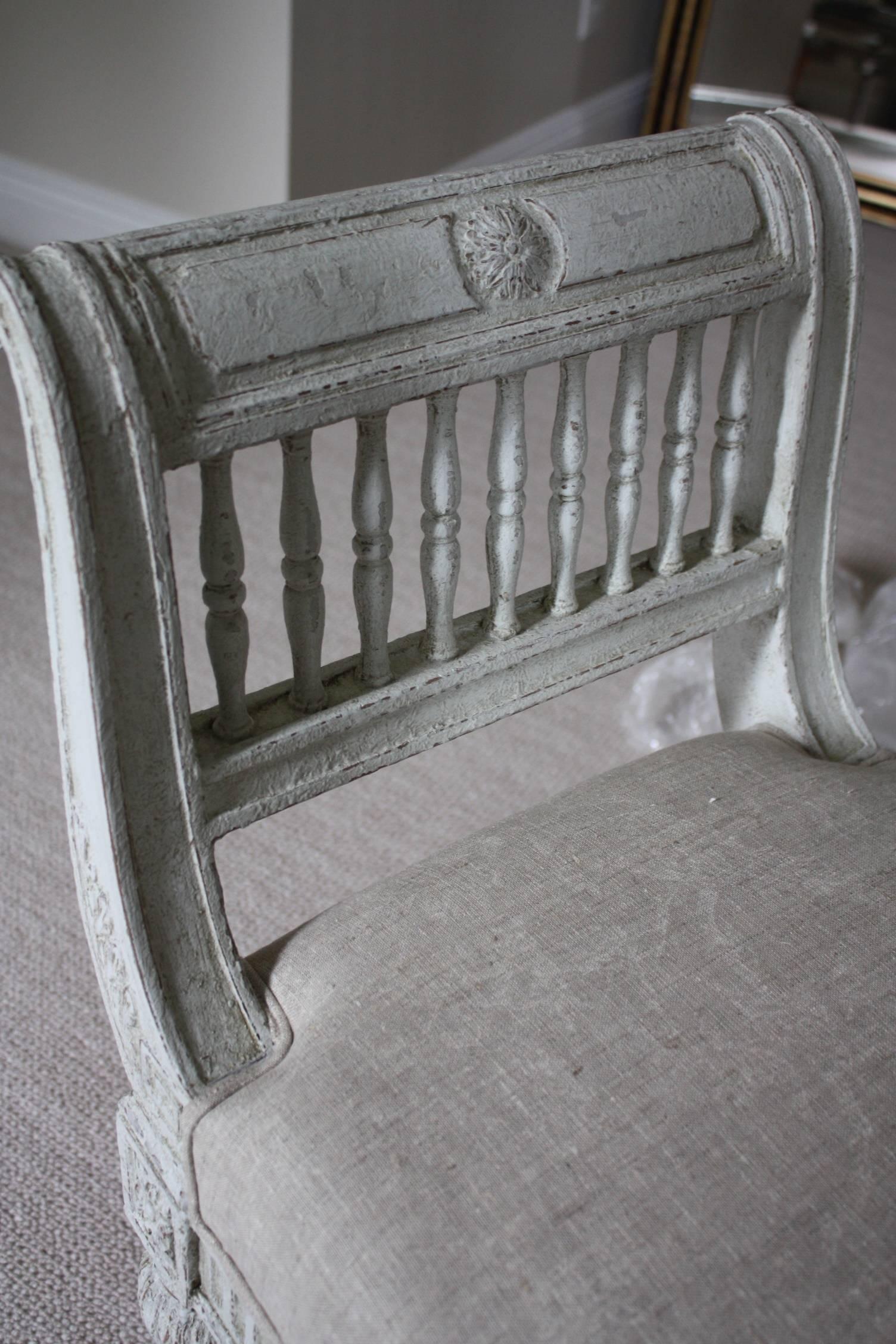 Crafted in France, circa 1880, the banquette features a curved back with spinals, detailed fluted carvings around the apron and tapered legs. The piece has been reupholstered with a gray linen fabric. Perfect addition to the foot of your bed.