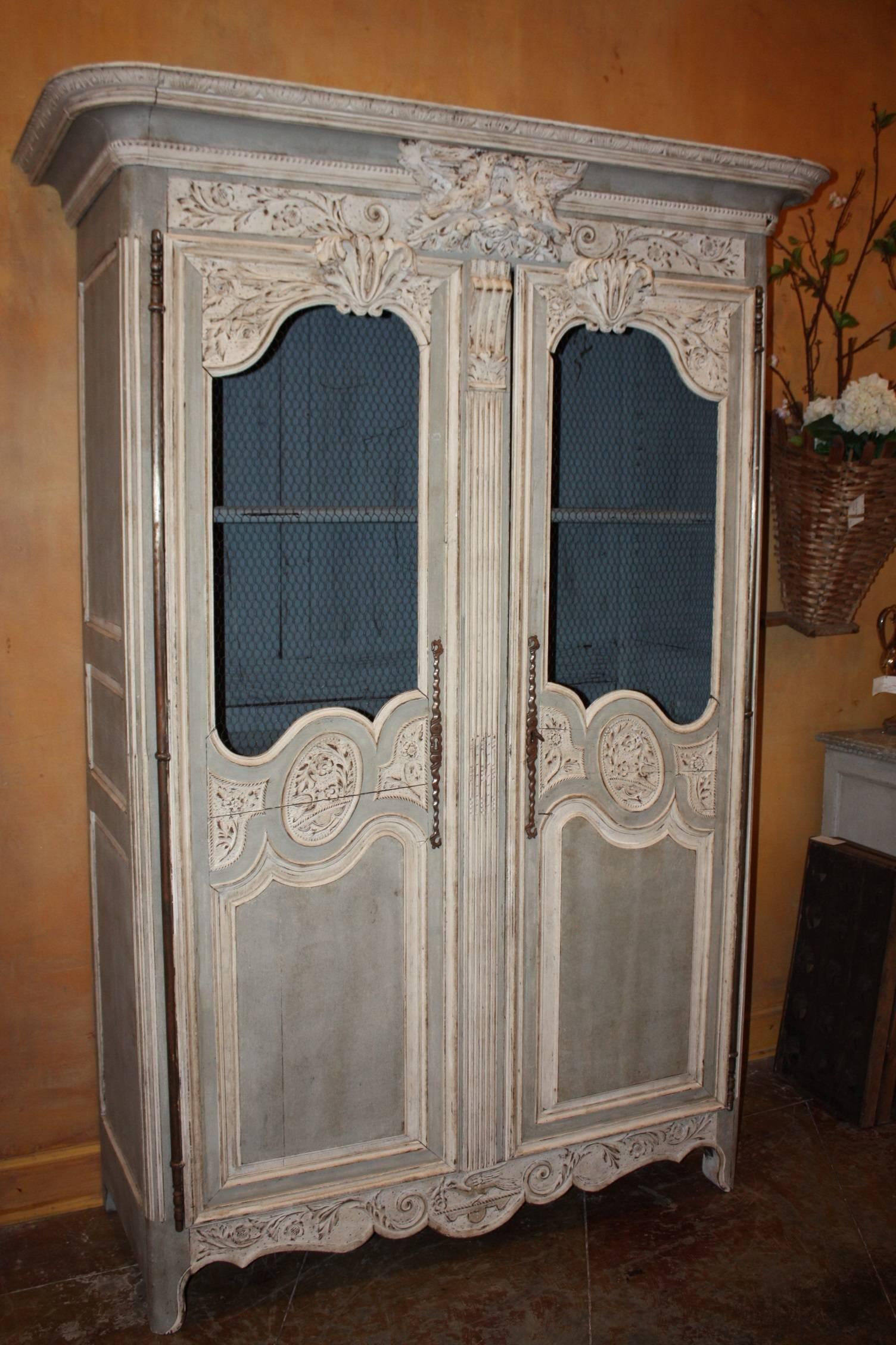 Beautifully carved French painted armoire featuring screened doors and delicate carvings such as an exceptional pair of lovebirds on the top crest. The armoire opens as great place for storage.