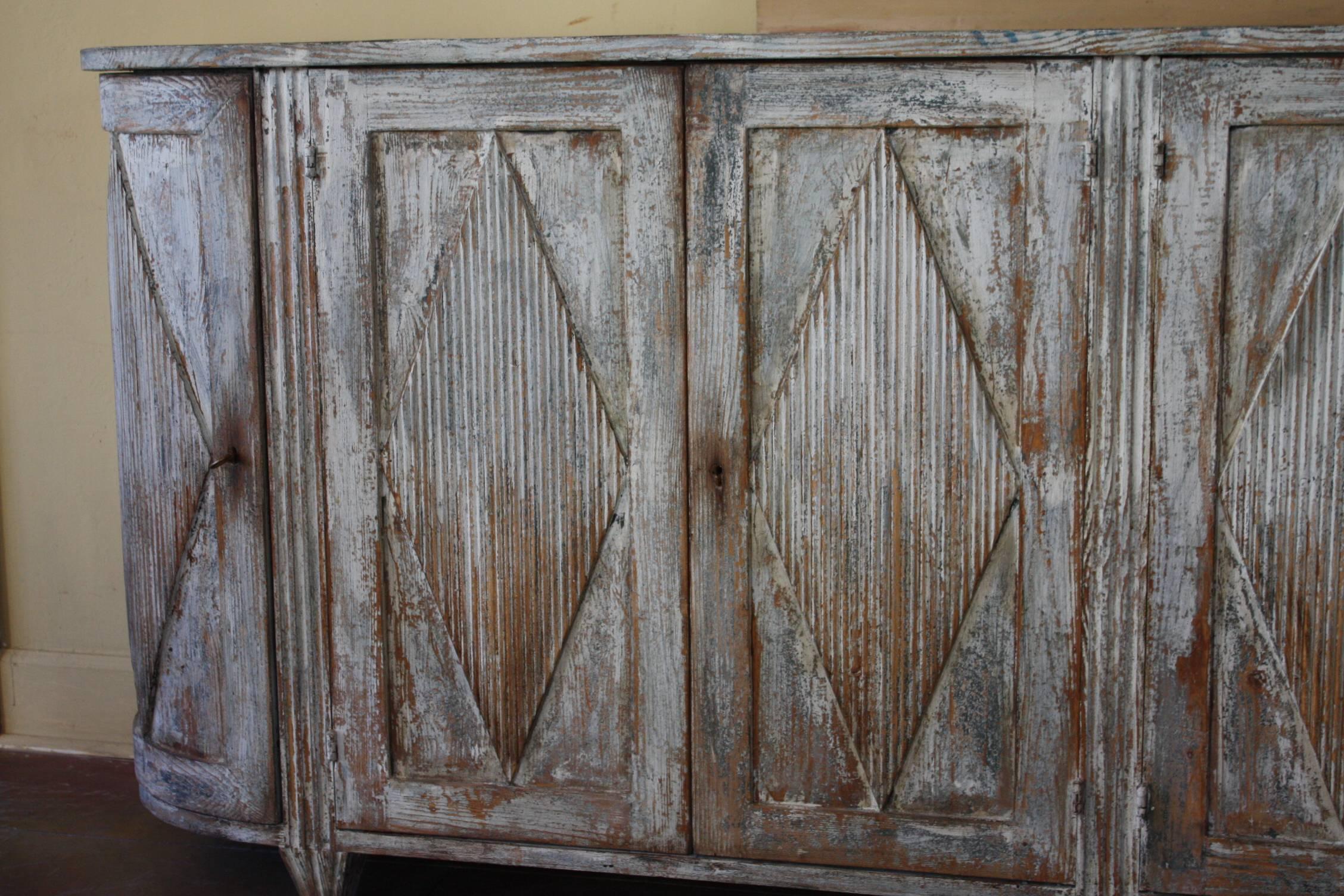 Swedish late 19th century enfilade or sideboard in a simple design and good scale, hand dry scraped to show traces of chalky white and pale blue paint.
The Swedish enfilade or sideboard has a very elegant curved form to the side, four doors to the