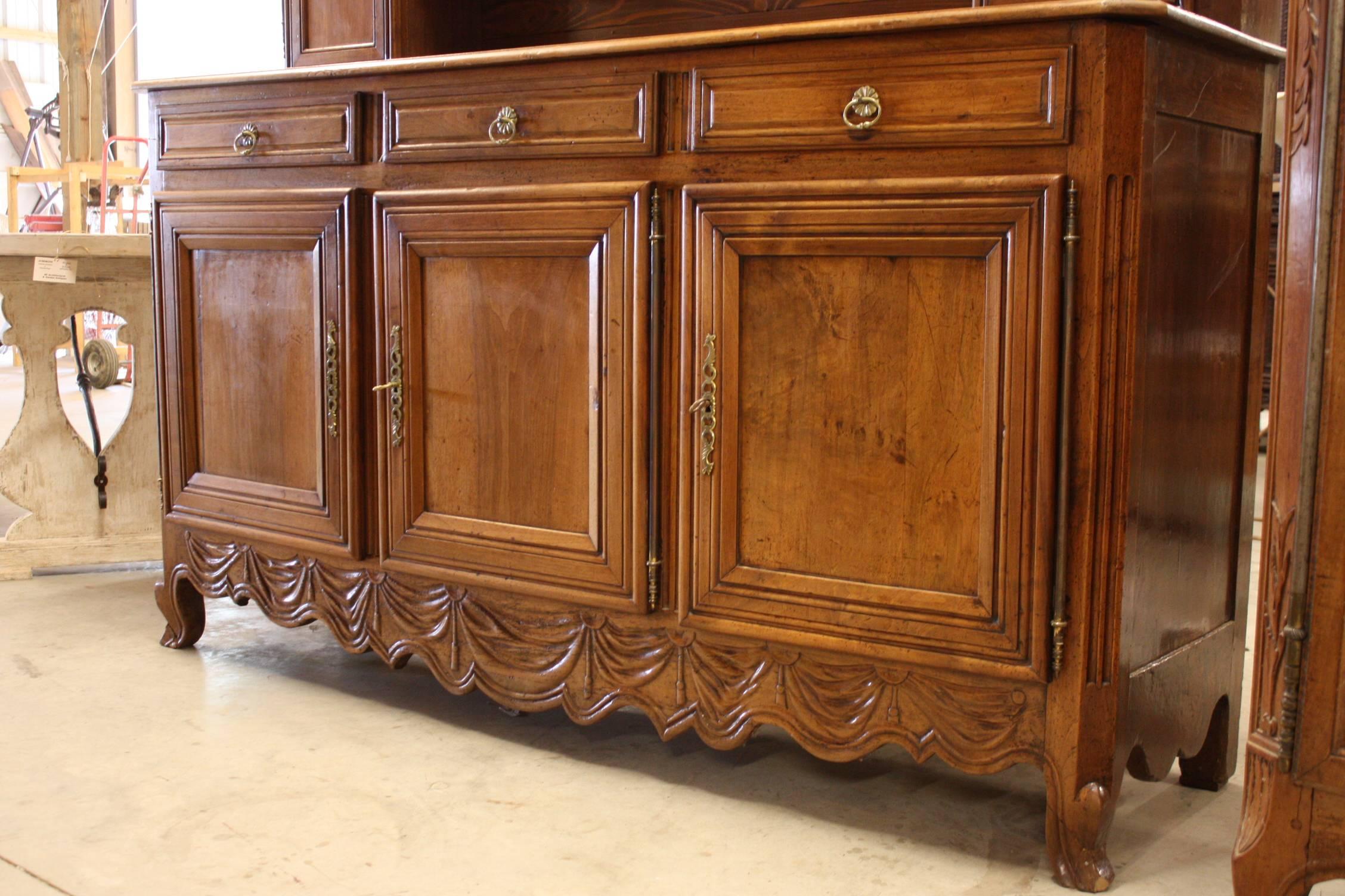 A fine Louis XV period vassellier in walnut with plate-rack, beautifully carved cornice and frieze, resting atop an Enfilade with three doors and three sliding drawers.