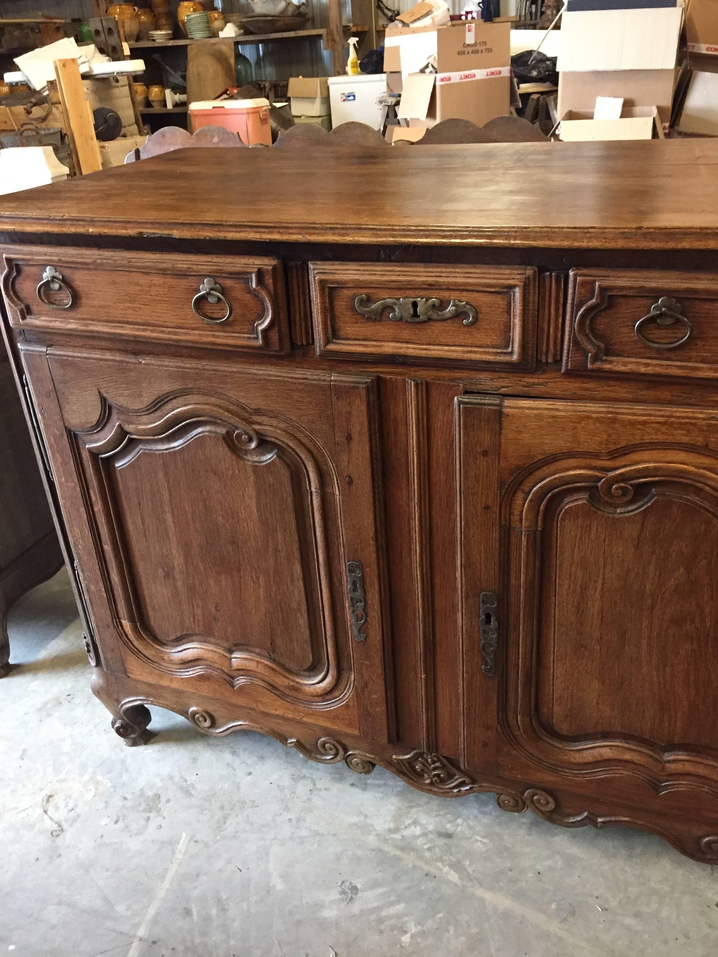 Hand-carved oak buffet with two drawers over a pair of paneled doors sitting on scroll feet. This charming 19th century buffet has its original hand-forged iron locks and keys with artisan made escutcheons pull and boasts a beautiful patina that