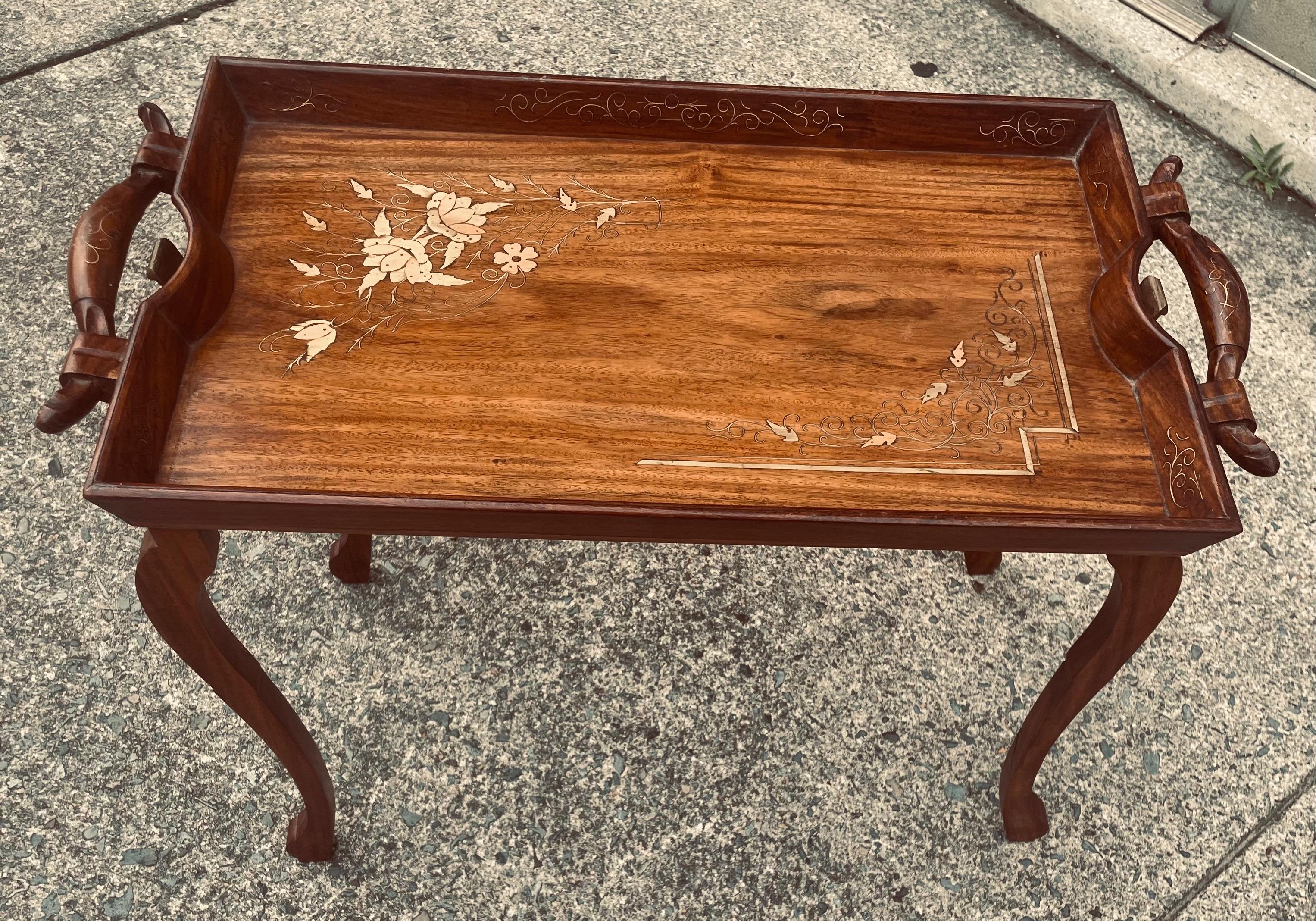 This is a gorgeous folding tray table crafted from rosewood with wonderfully inlayed brass and copper floral and leaf coordinating patterns on opposite corners and lovely delicate scroll designs along the raised sides of the tray and on the handles.