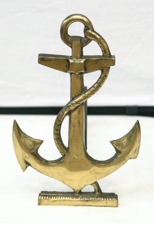 Cast brass fireplace andirons in the form of anchors with draping rope.