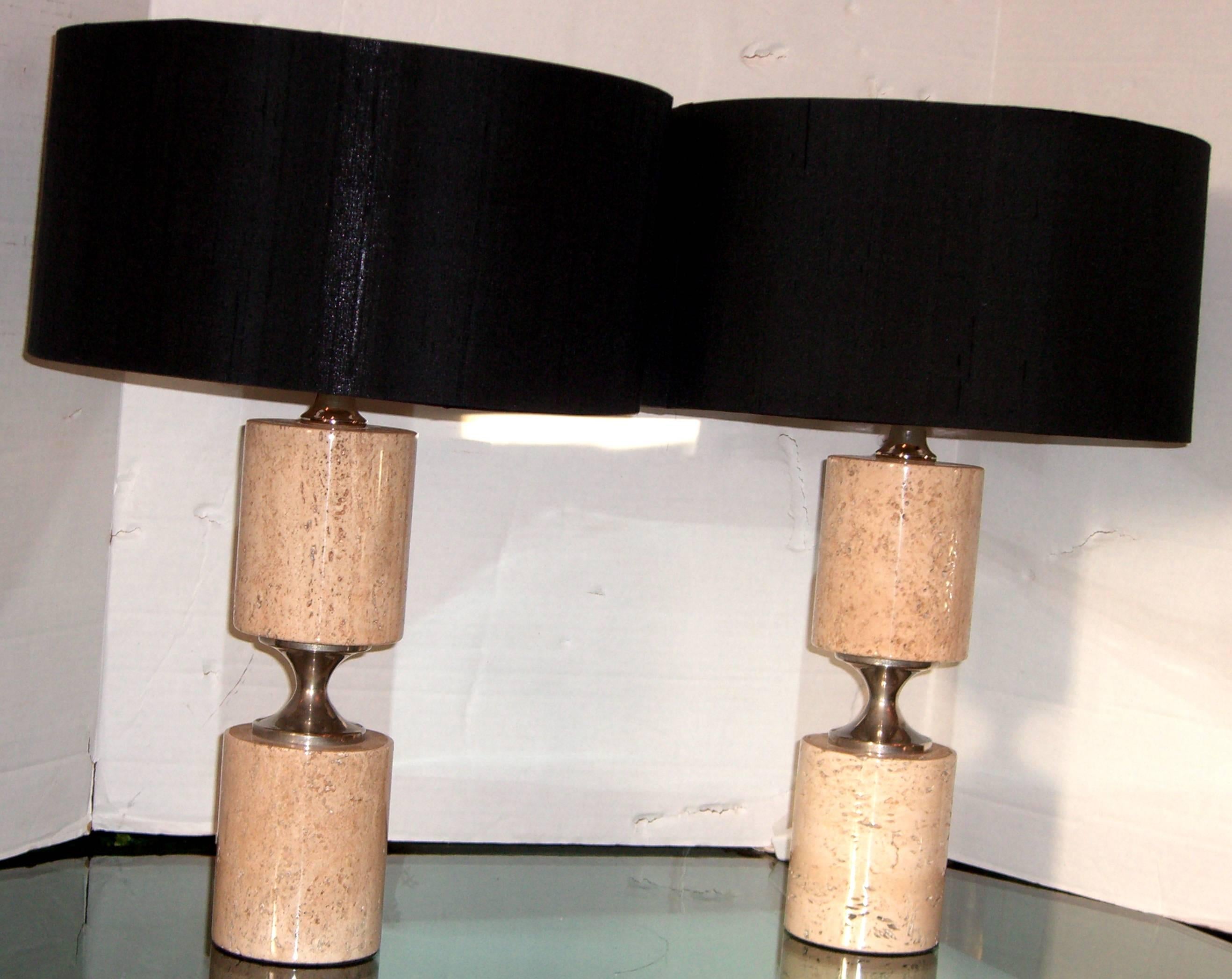 A pair of cylindrical form taupe tone natural stone table lamps. The center is a hourglass shaped nickel. New silk shades in black have been added. All wiring is new for the US.