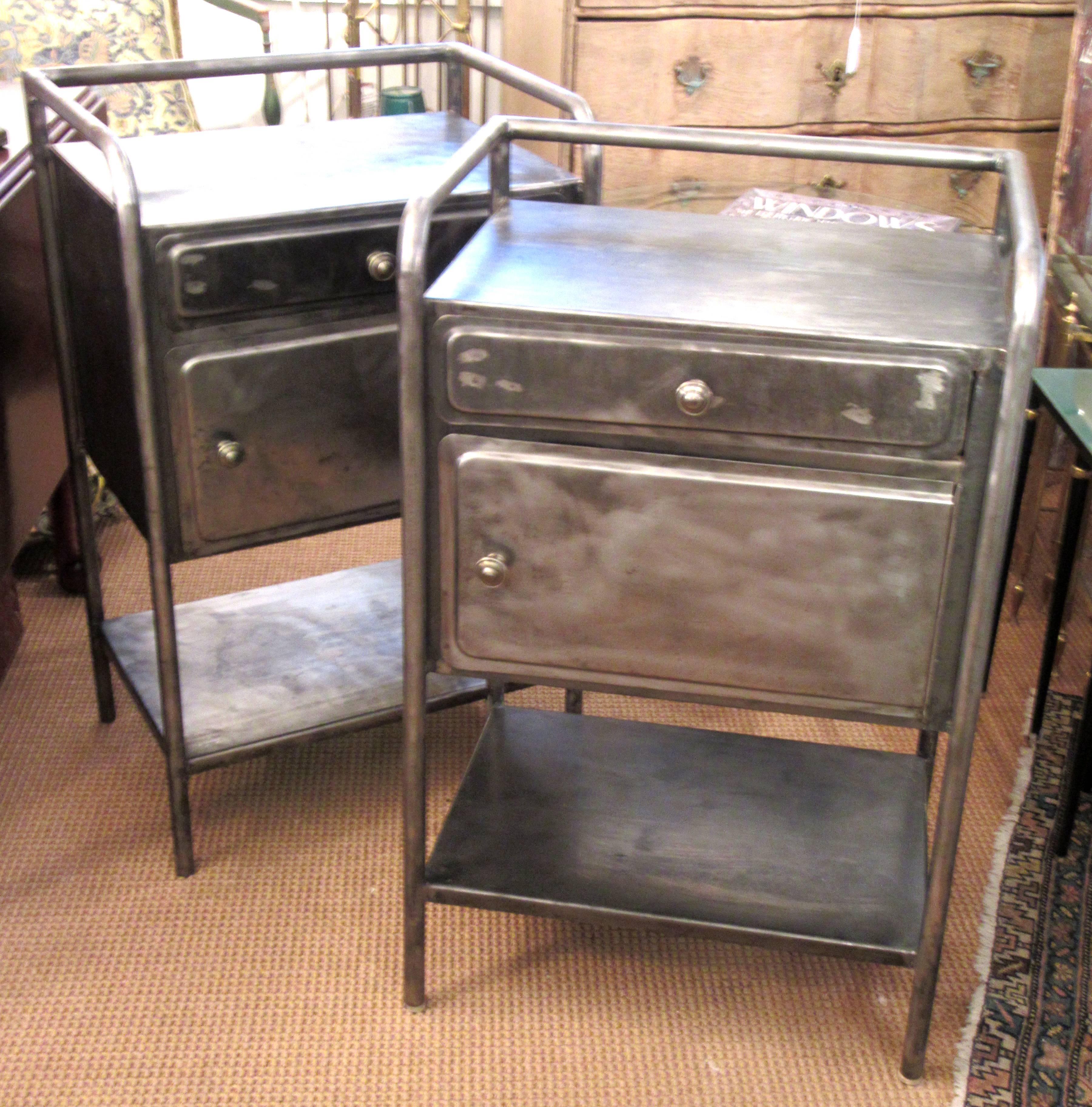 A pair of bare steel bed/side tables, each with one drawer and one storage space with right hinged door.