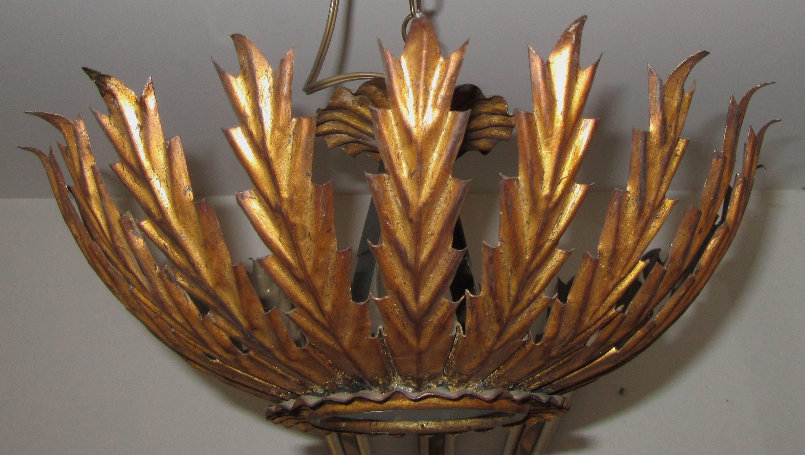 A lovely, semi flush mount hand-cut and gilded metal sunburst form light. Re wired with a single candelabra size bulb socket with a frosted glass shade.
The socket can take up to a 60 watt bulb. A canopy and chain is included.