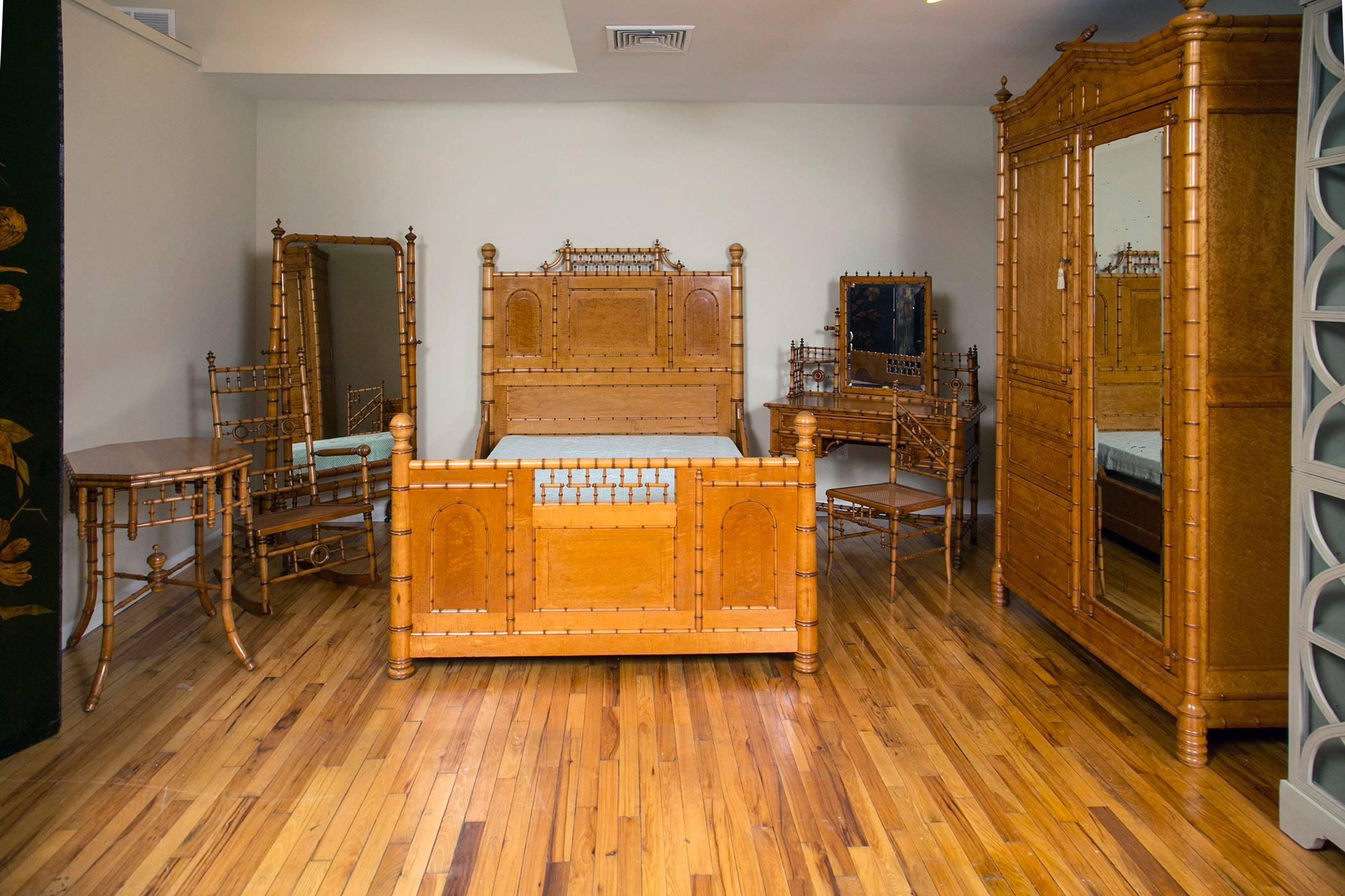 The principal piece in this rare collection of late 19th century golden stained bird's-eye maple faux bamboo bedroom furniture. The full size bed with a spindled crest, paneled head and foot-board, the uprights having ball finials with conforming