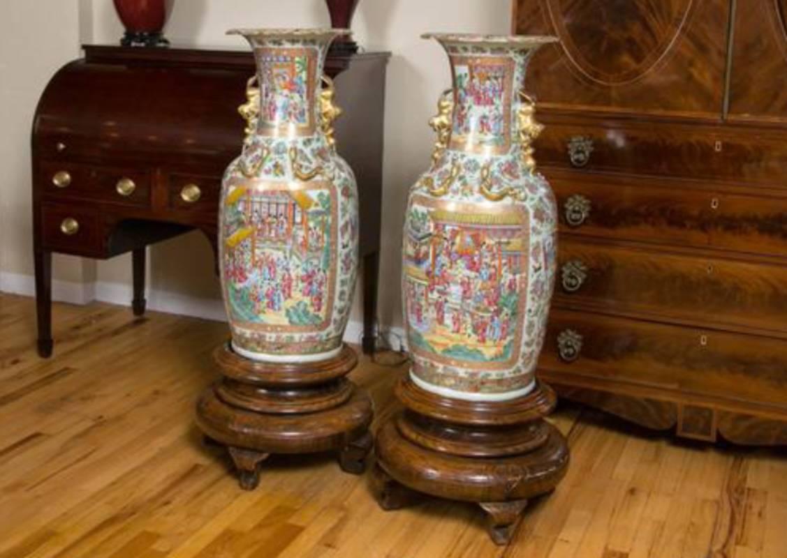 A fine pair of large Cantonese Famille Rose, specifically Rose Mandarin, vases. Of baluster form with a trumpet neck, dogs of fo handles, and raised gilt Chiang Dragon on the neck and shoulders. Polychrome enameled and gilded with scenes of court