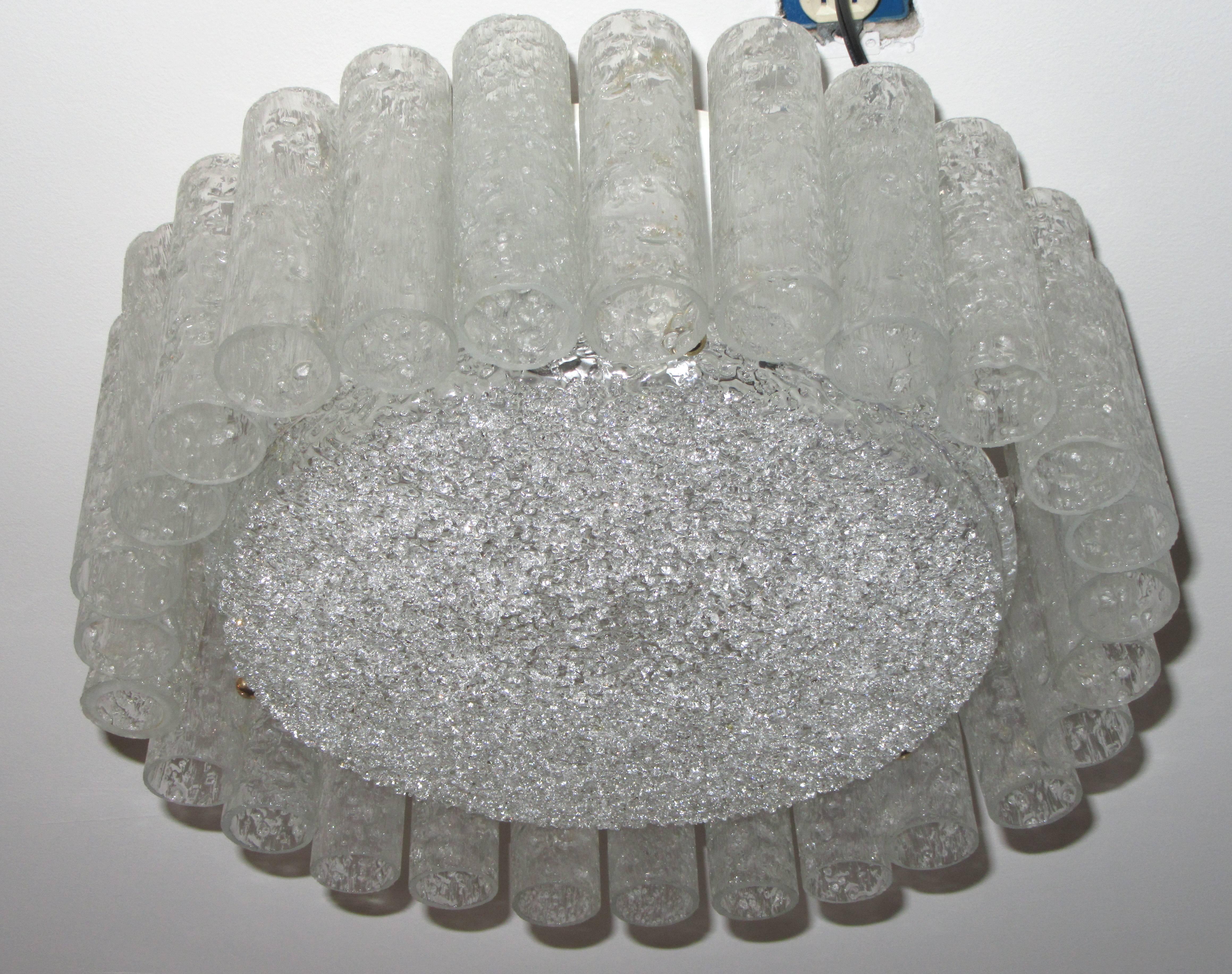 A Mid-Century ceiling light designed in the 1960s and manufactured by Doria Leuchten of West Germany. It features a white lacquered metal base with six sockets candelabra bulbs and hooks for 35 ice glass tubes. The middle disc is surrounded by