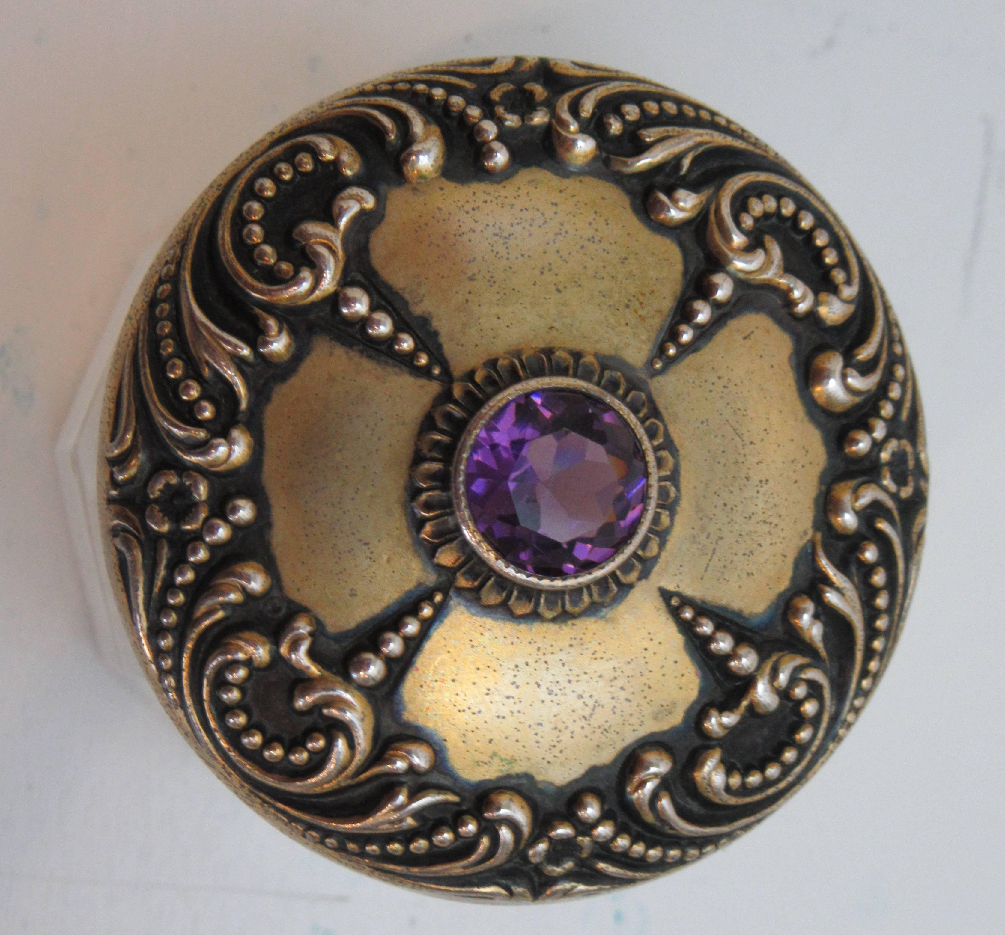A petite glass jar with a sterling Art Nouveau pattern lid. The center of the lid is fitted with a faceted glass 