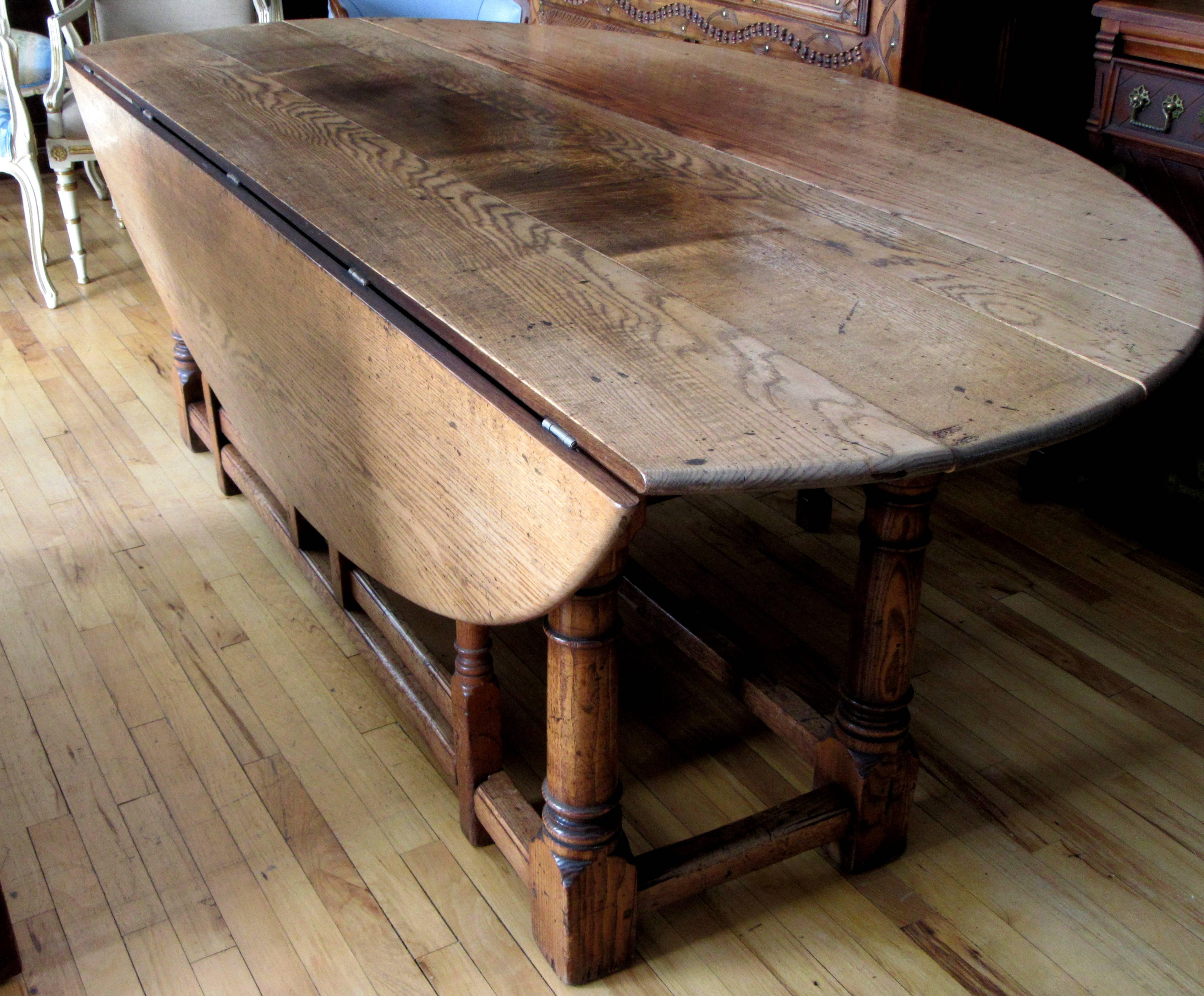 19th century English oak double gateleg hunt table, the rectangular top with rounded ends flanked with oval or D-shaped drops, above a scalloped apron and rising on turned legs conjoined by the box stretcher.