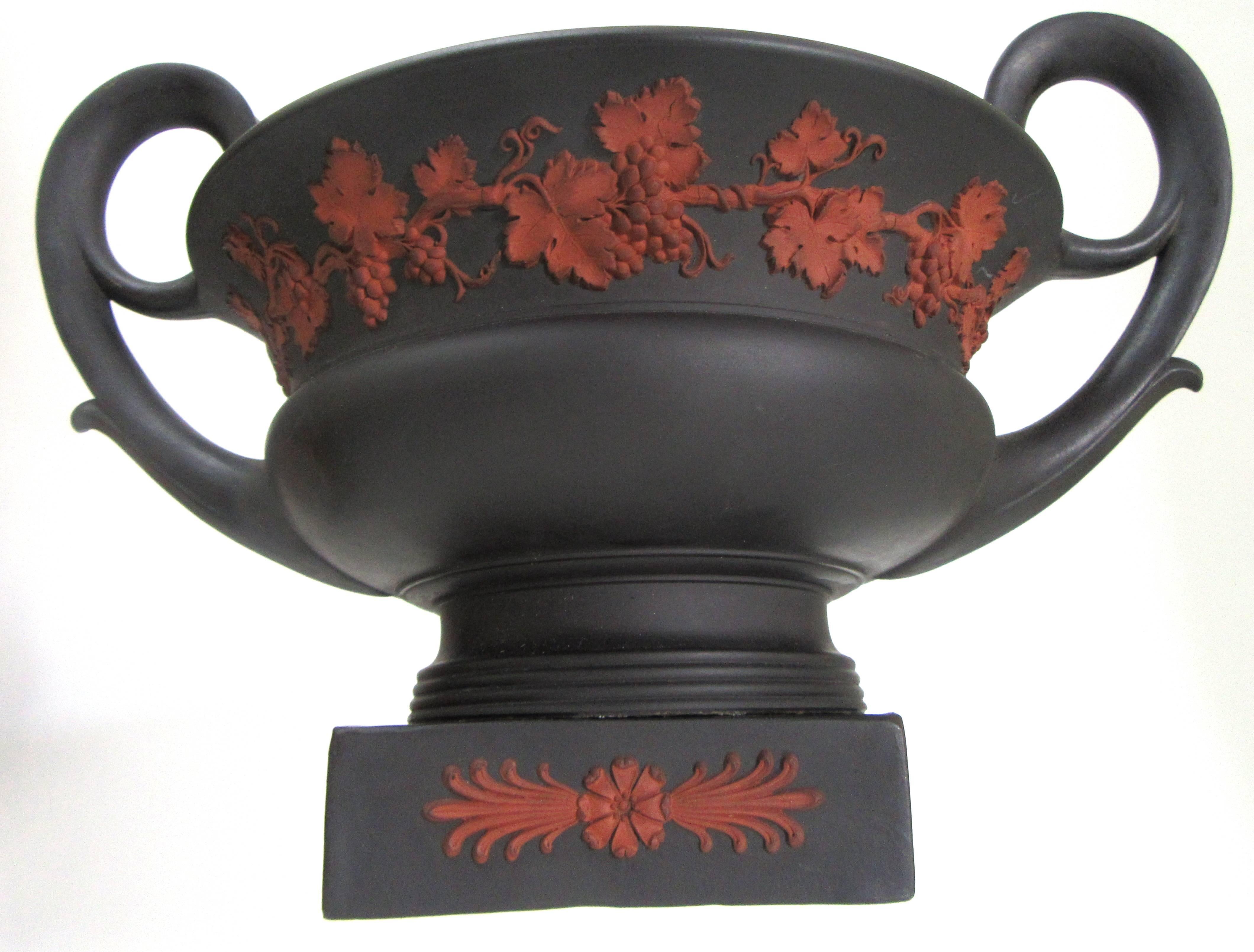 Wedgwood black basalt bough pot with lid. The pot with scrolled loop handles, applied rosso antico foliate relief. Impressed under the base Wedgwood and the date letter F.