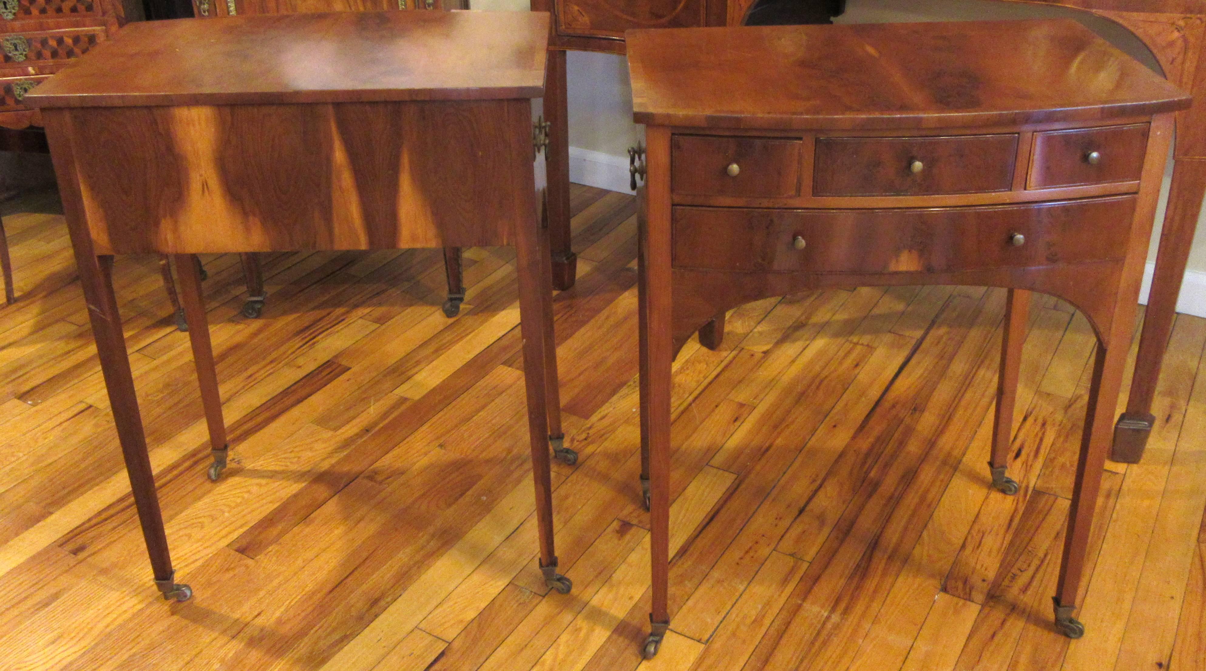 A pair of nicely proportioned four-drawer tables on brass casters. Flame mahogany veneer with original brass hardware.
