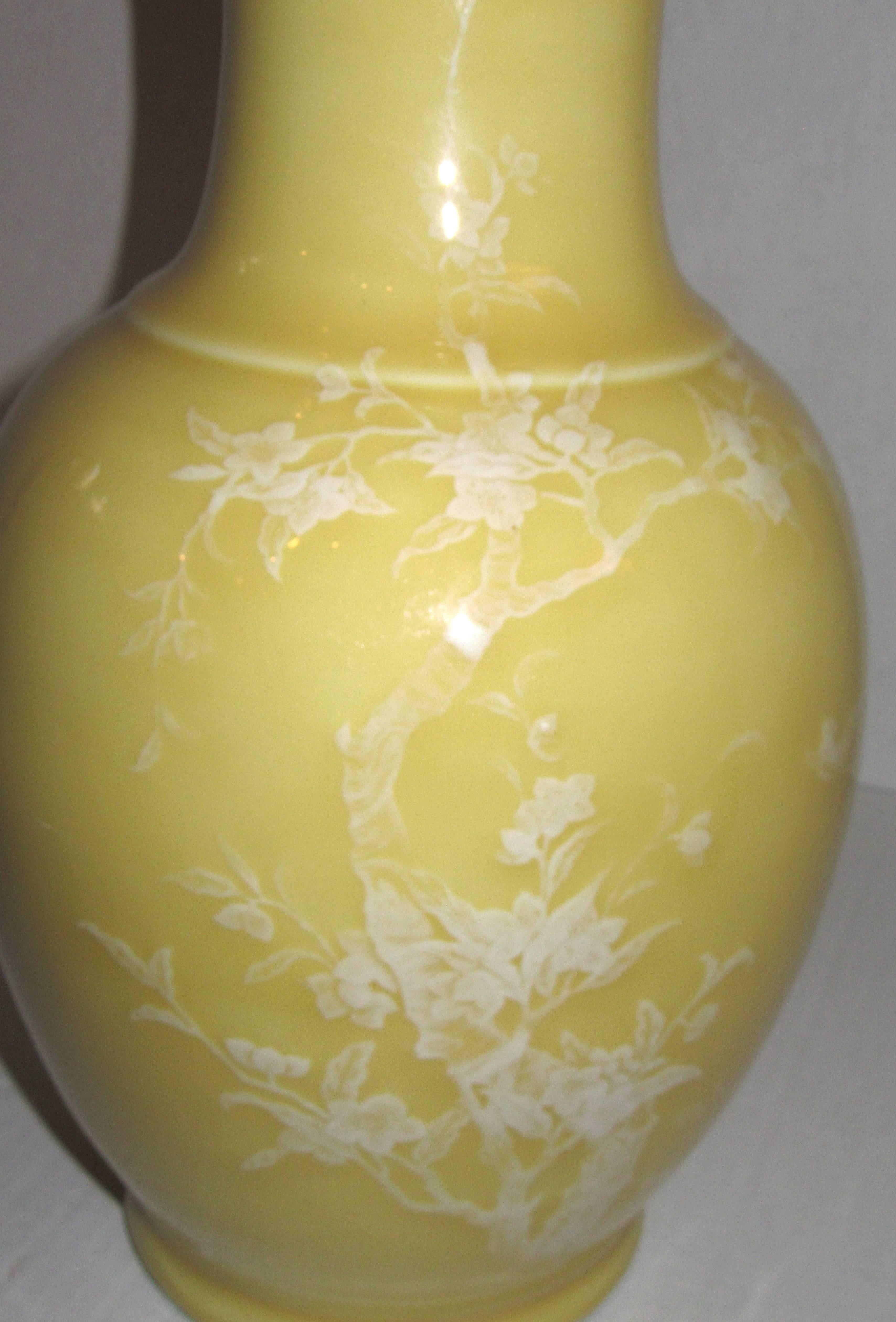 A porcelain high shine glazed vase with enamel hand painting of flowering trees and birds in textured relief.
 